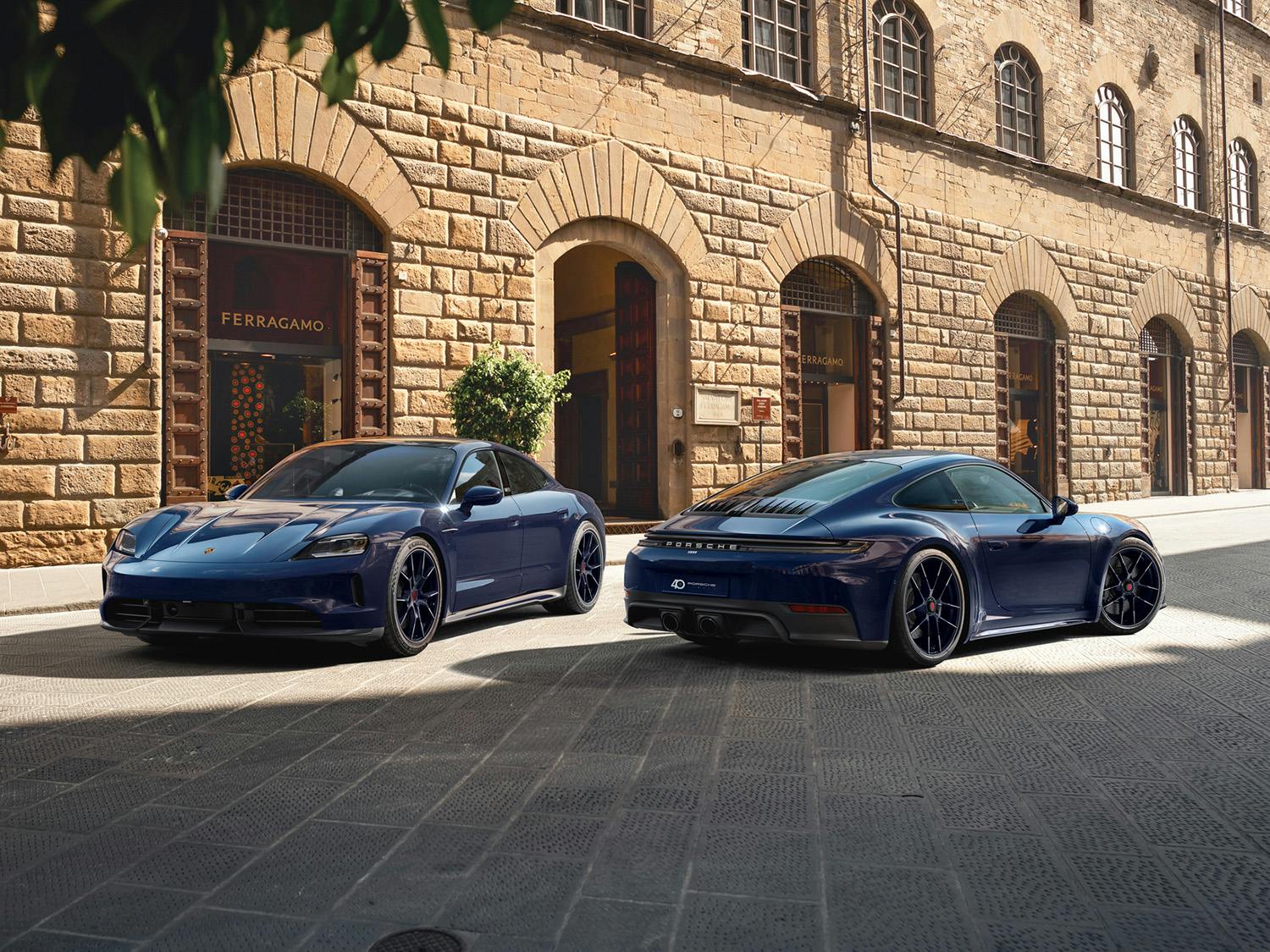911 Carrera 4 GTS and Taycan 4 S Ferragamo Edition in blusogno colour, parked in front of a historic building in Italy.