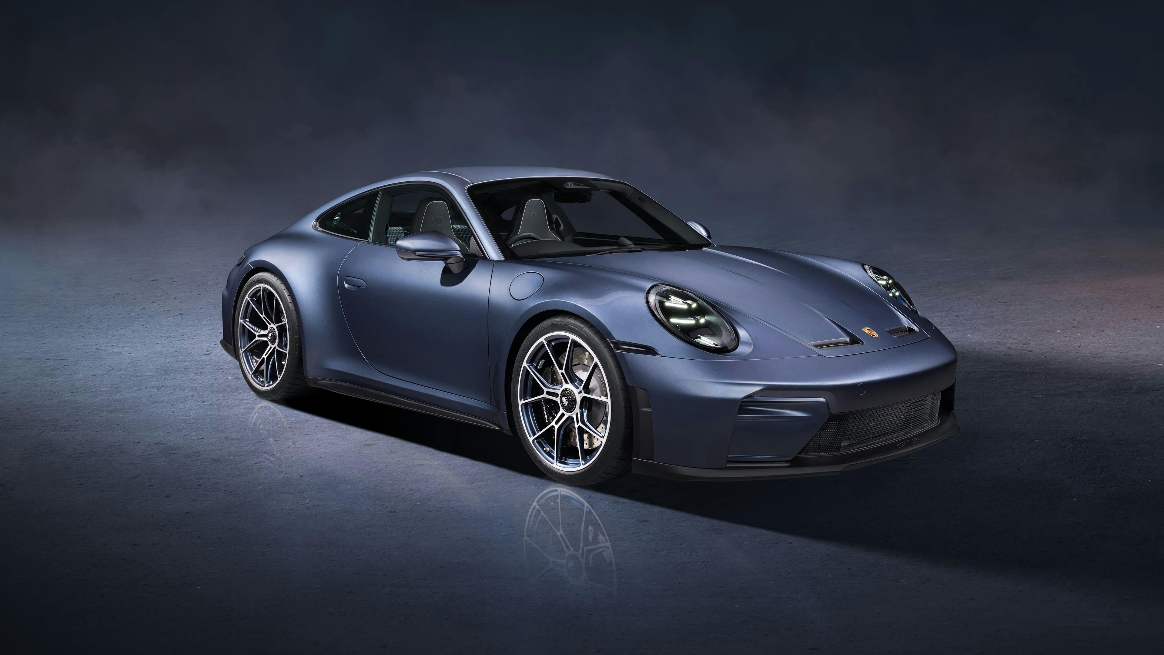 Blue-grey Porsche vehicle photographed in a studio setting with dramatic lighting and a dark gradient background.