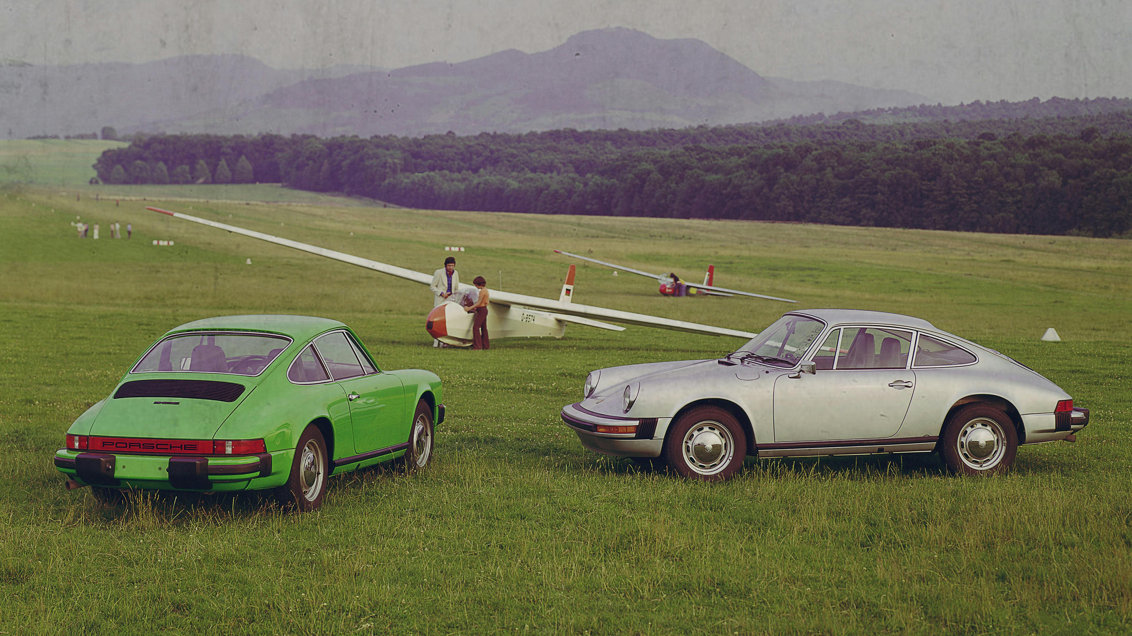 Two Porsche 912 Es on a meadow with gliders.