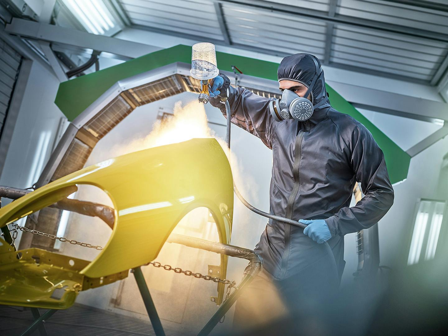 Empleado Porsche pintando una pieza de un vehículo.