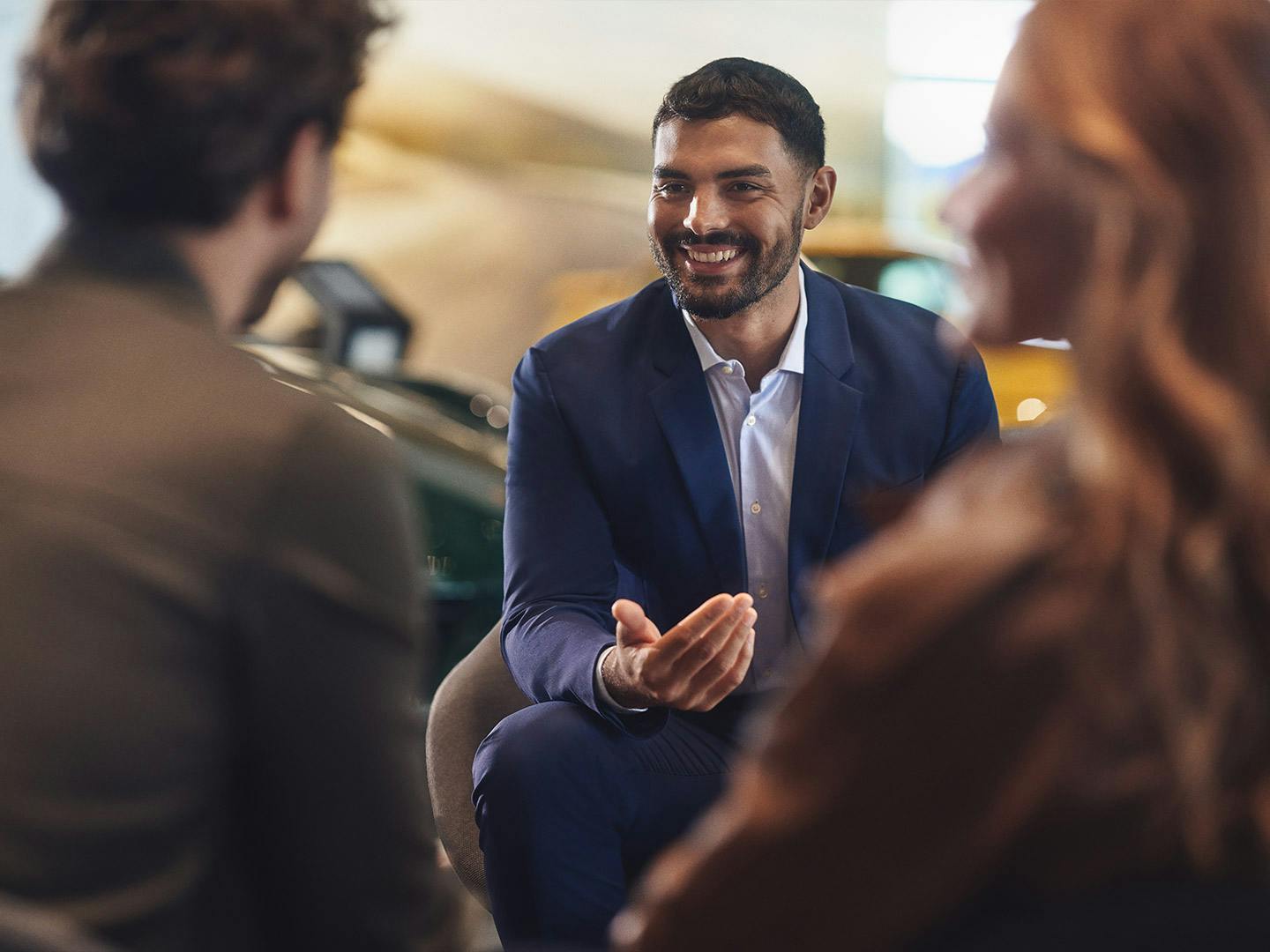 Un conseiller Porsche est en train de discuter avec deux clients.