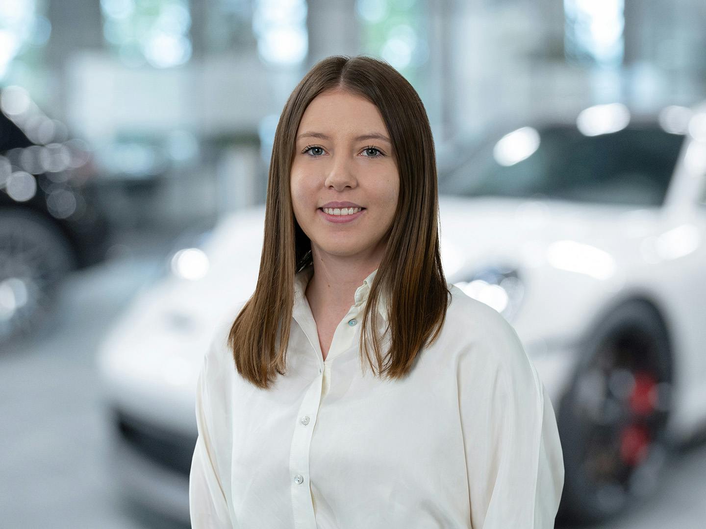 Porsche Mitarbeiterin berät einen Kunden der in einem Porsche Fahrzeug sitzt.