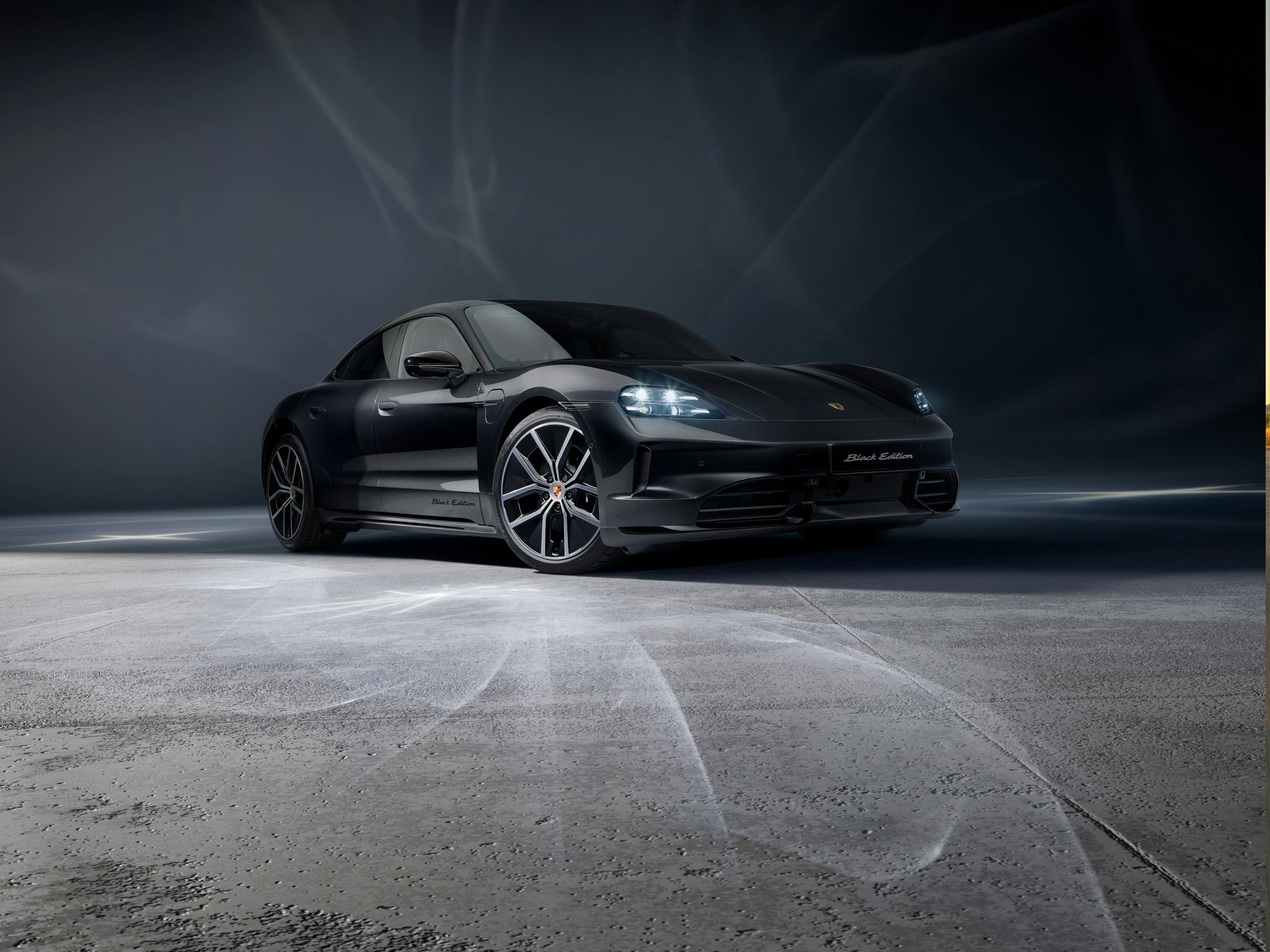 Taycan 4S Black Edition parked in a studio, facing the front with its lights on.