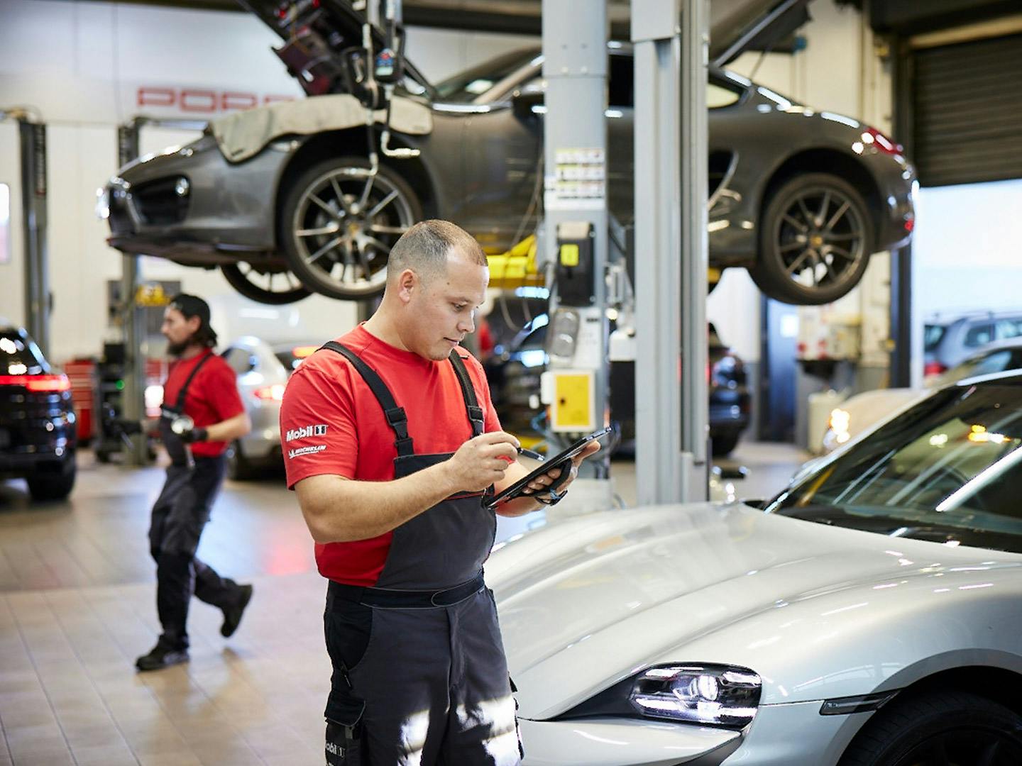 Technician diagnosing vehicle on tablet in a workshop