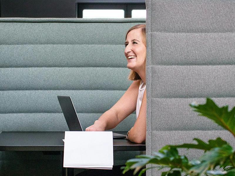 A woman is looking up from her laptop, laughing.