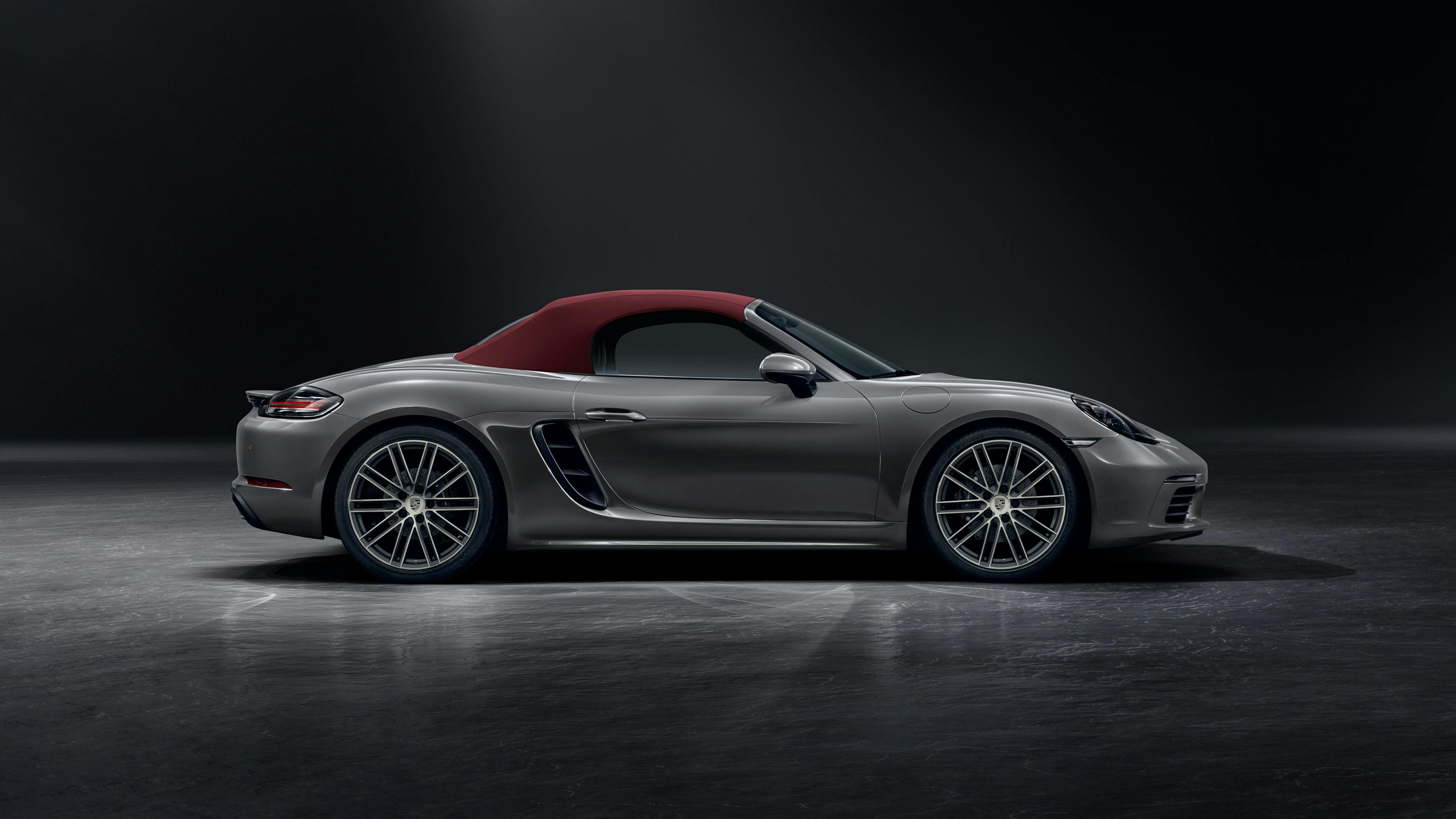 Une Porsche 718 Boxster noire de profil / vue latérale dans un studio sombre.