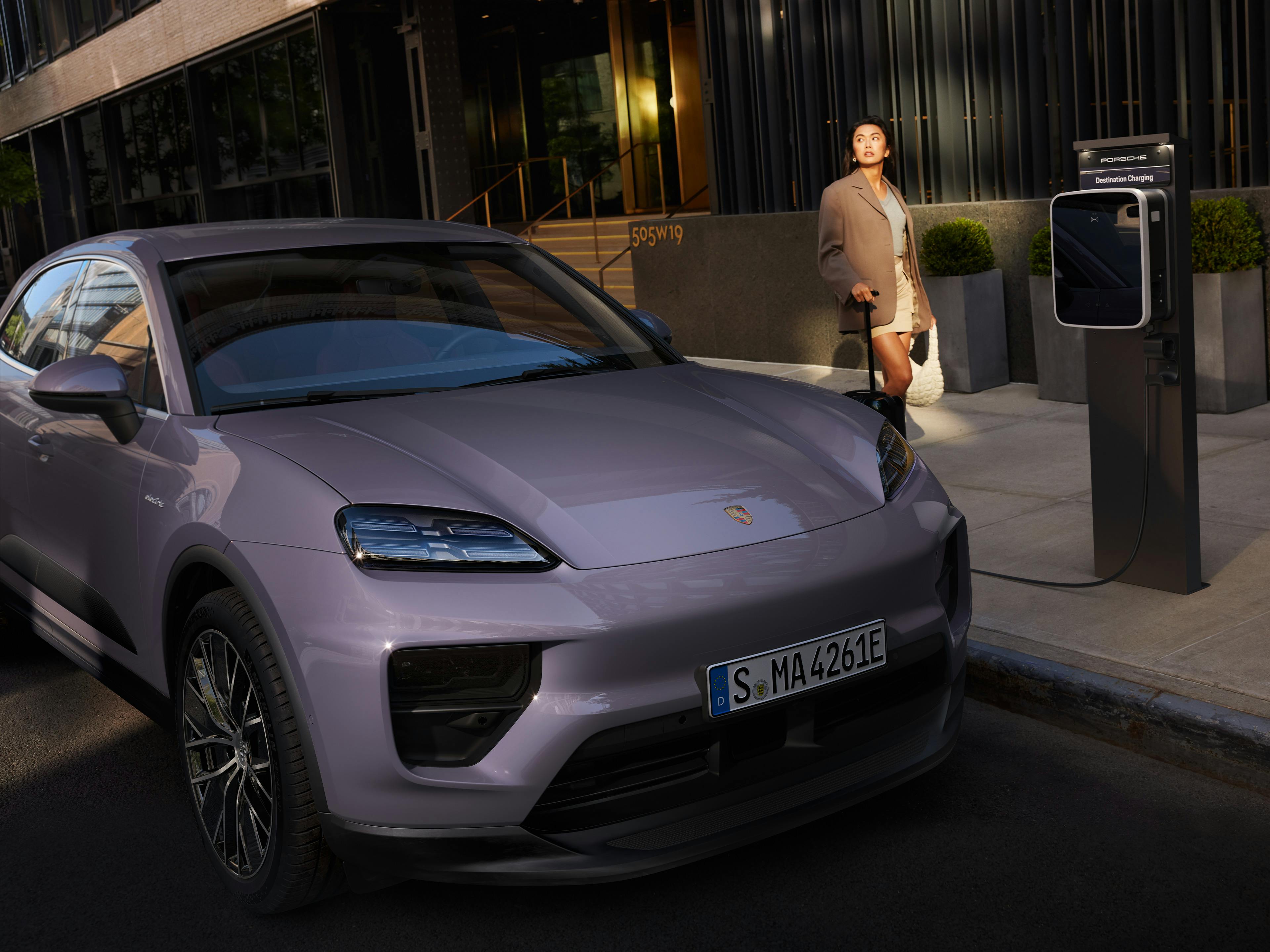 A Porsche Macan parked on the street and plugged into a Porsche Destination Charging unit.