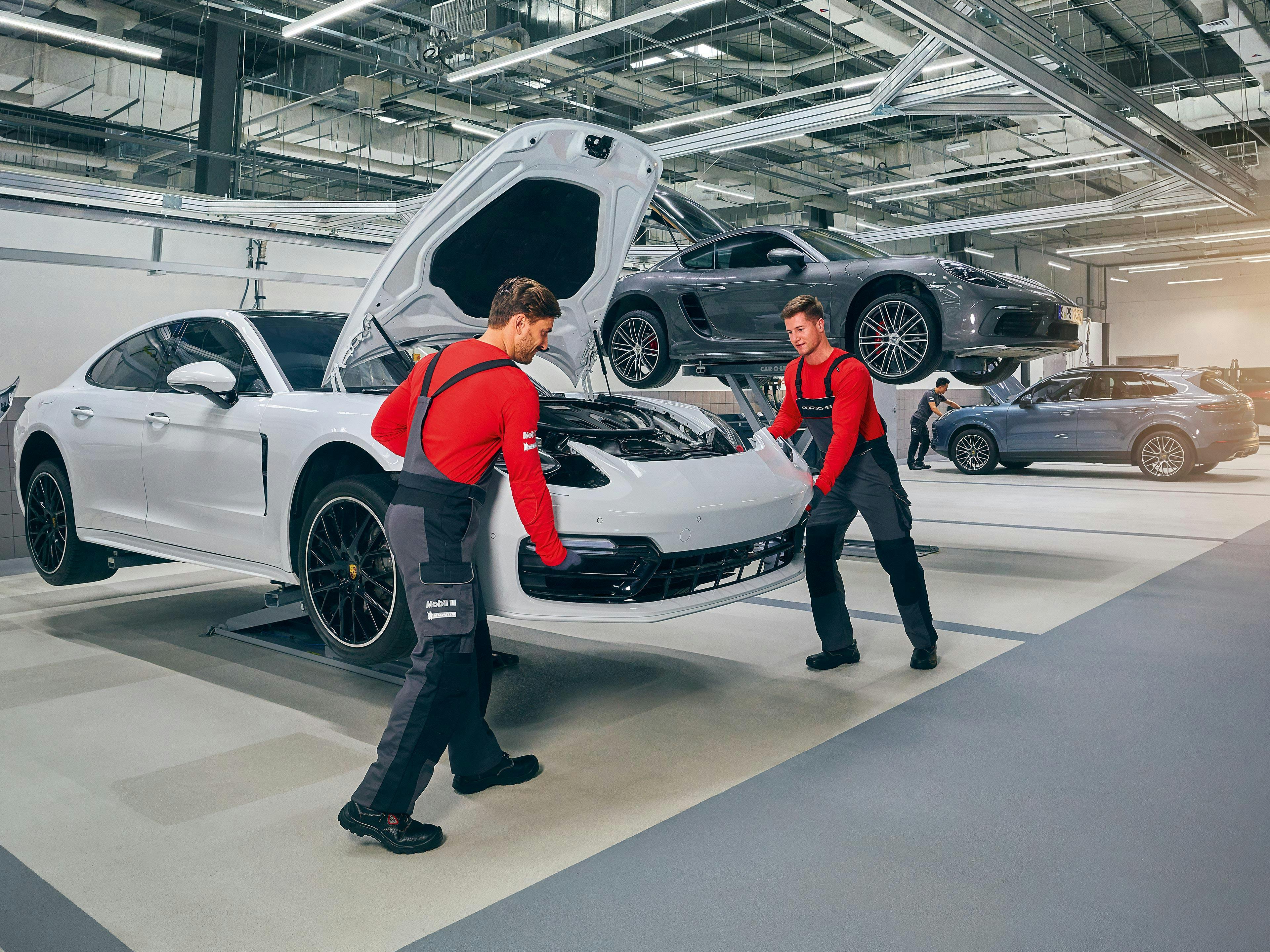 Porsche technicians working in a workshop on Porsche vehicles.