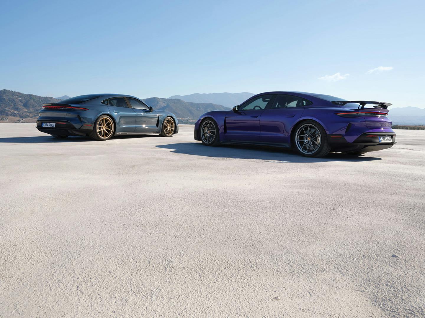 Twee porsches op een open vlakte met bergen in de verte