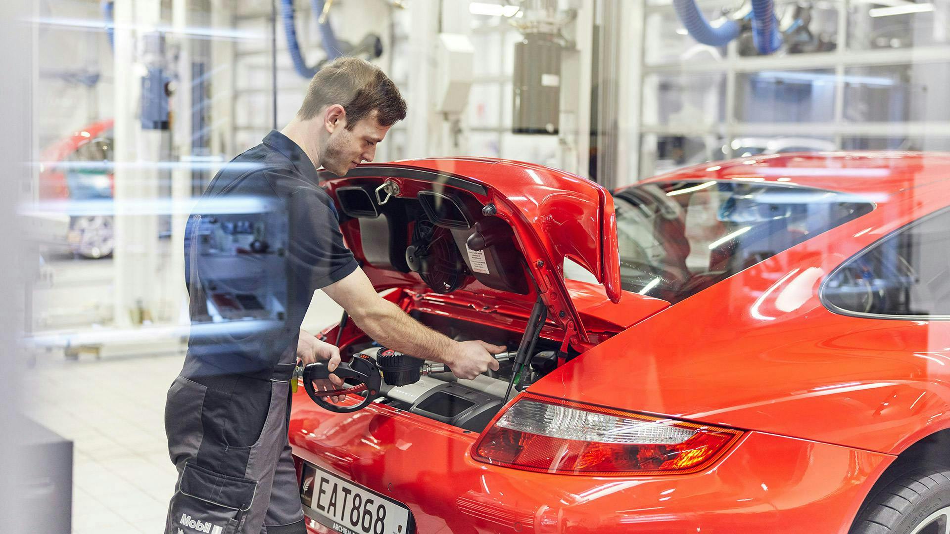 Porsche technician working on a red classic Porsche vehicle