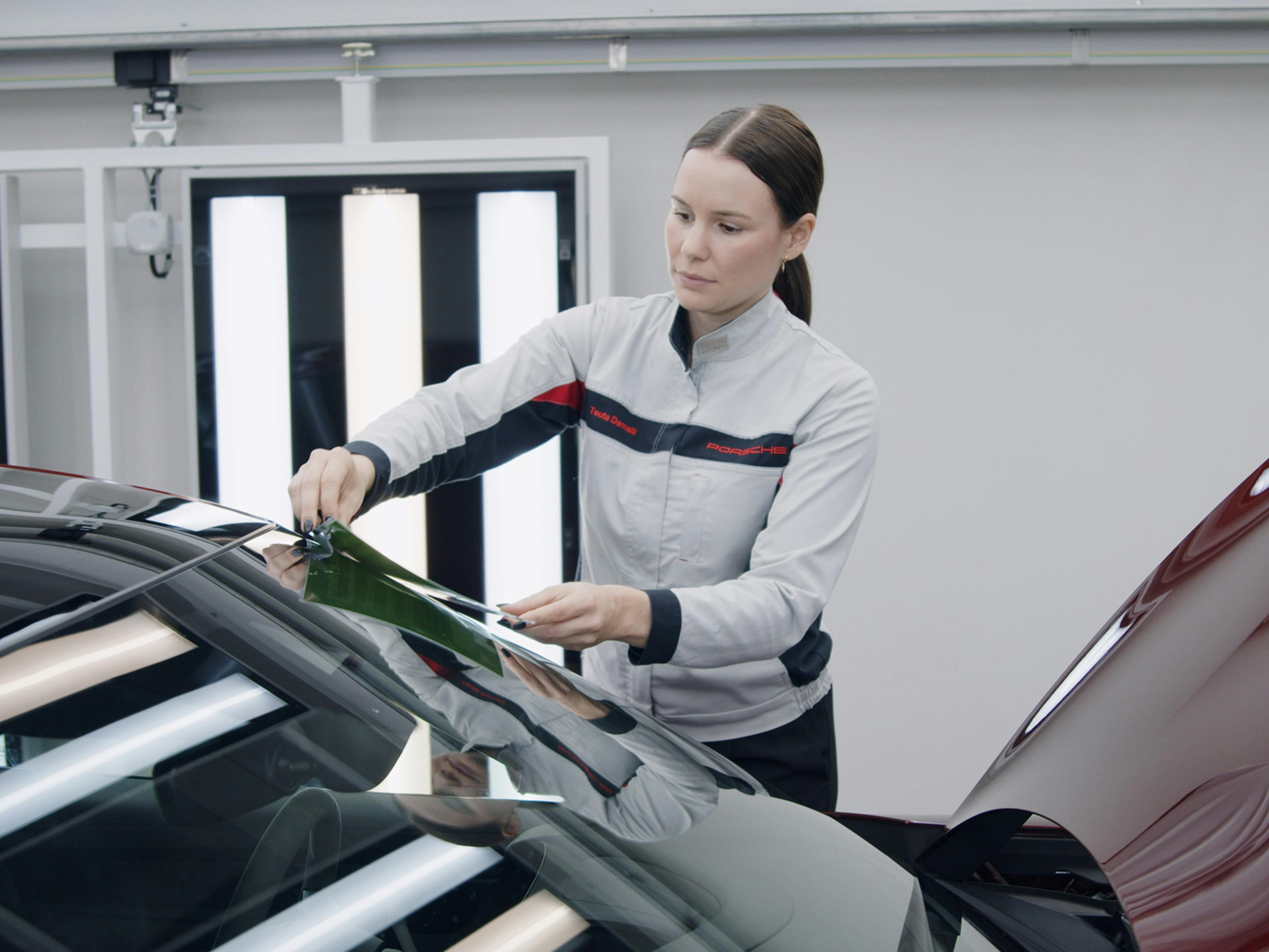 Die Porsche Mitarbeiterin Teuta bringt eine Folie auf ein Fahrzeug in der Montage an.