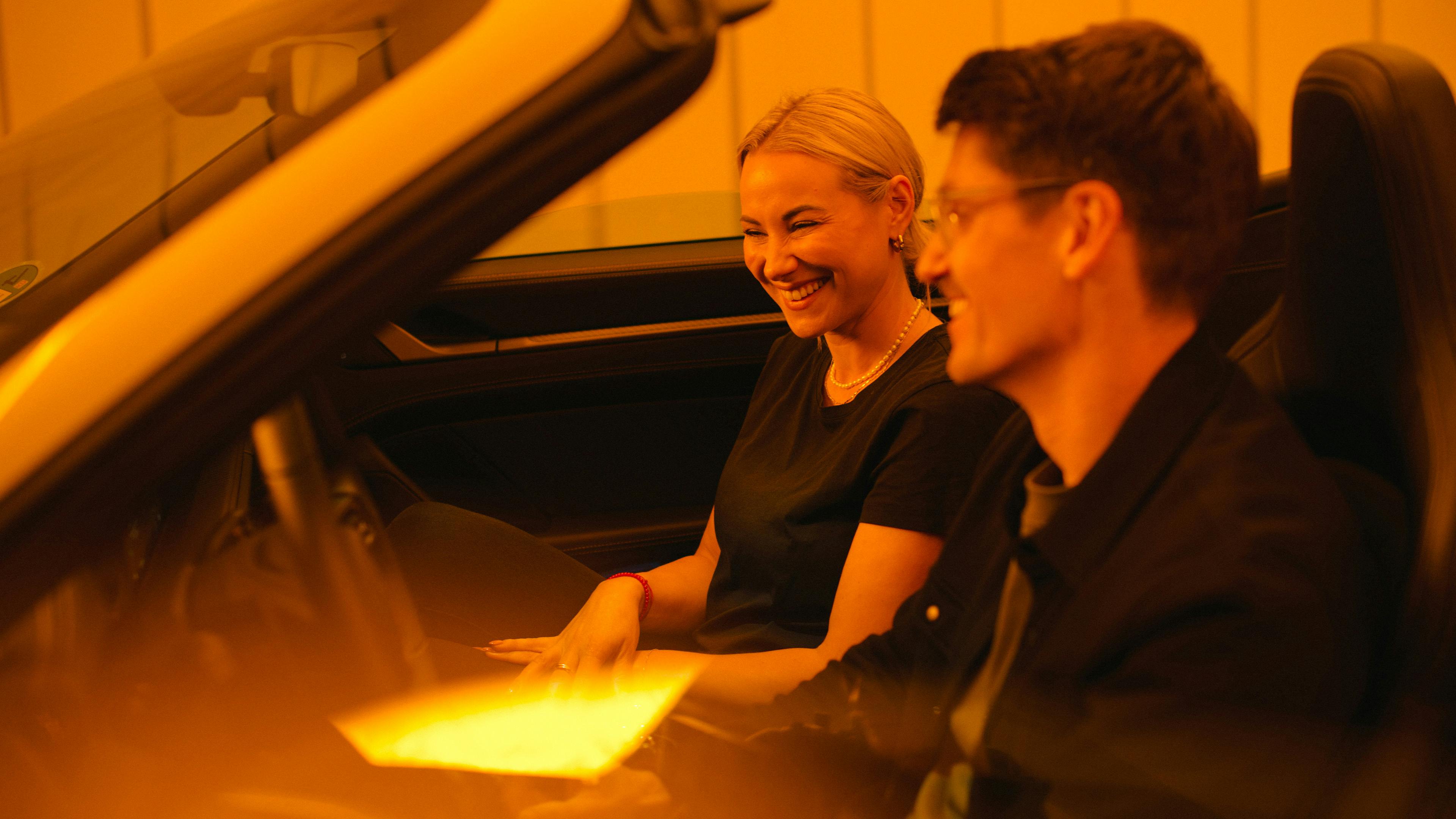 Porsche Mitarbeiter Sandra und Philipp prüfen gemeinsam Funktionen im Porsche 911 Turbo S Cabriolet.