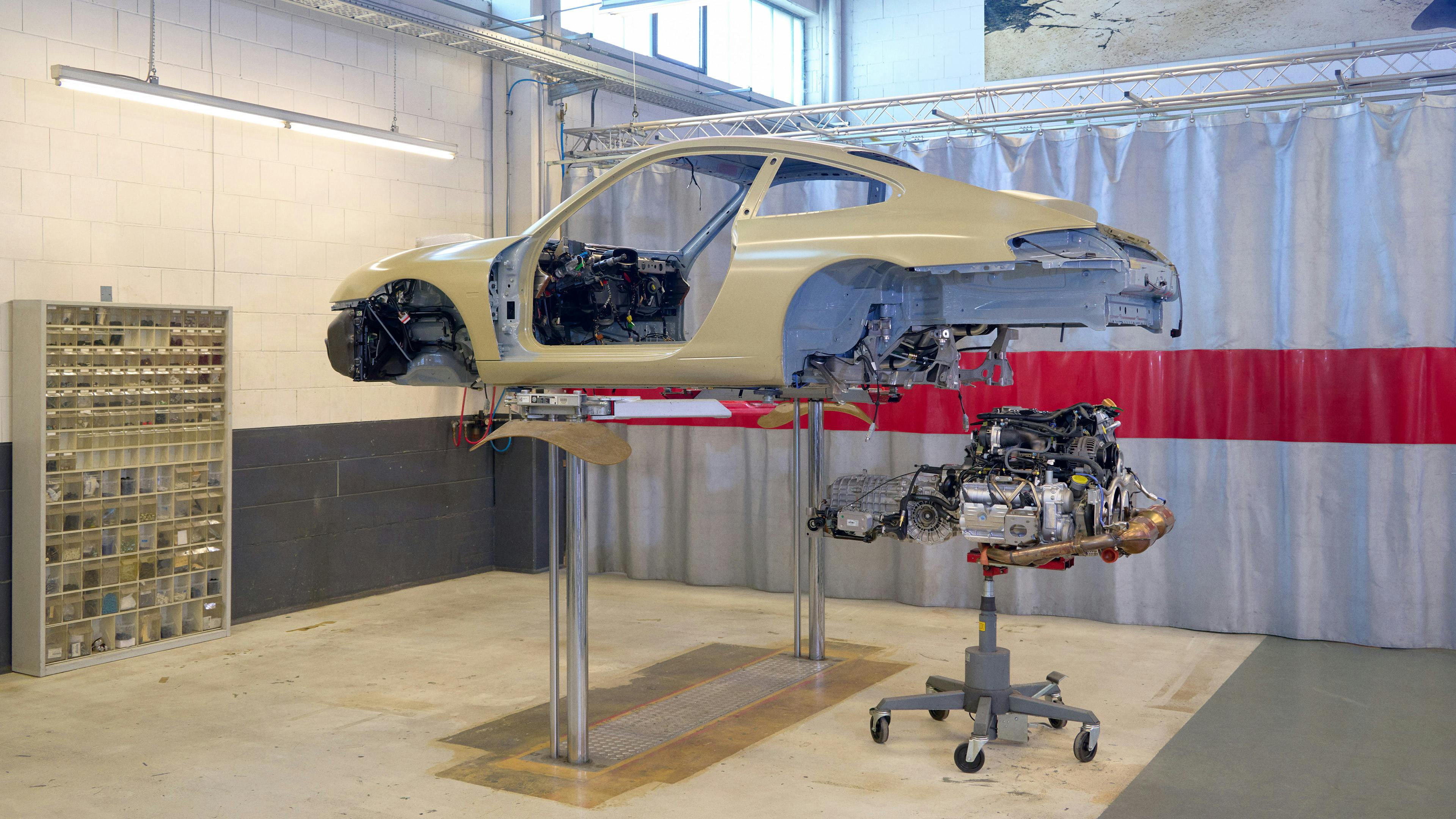 Workshop scene: Porsche bodyshell on a jack, naturally aspirated engine.