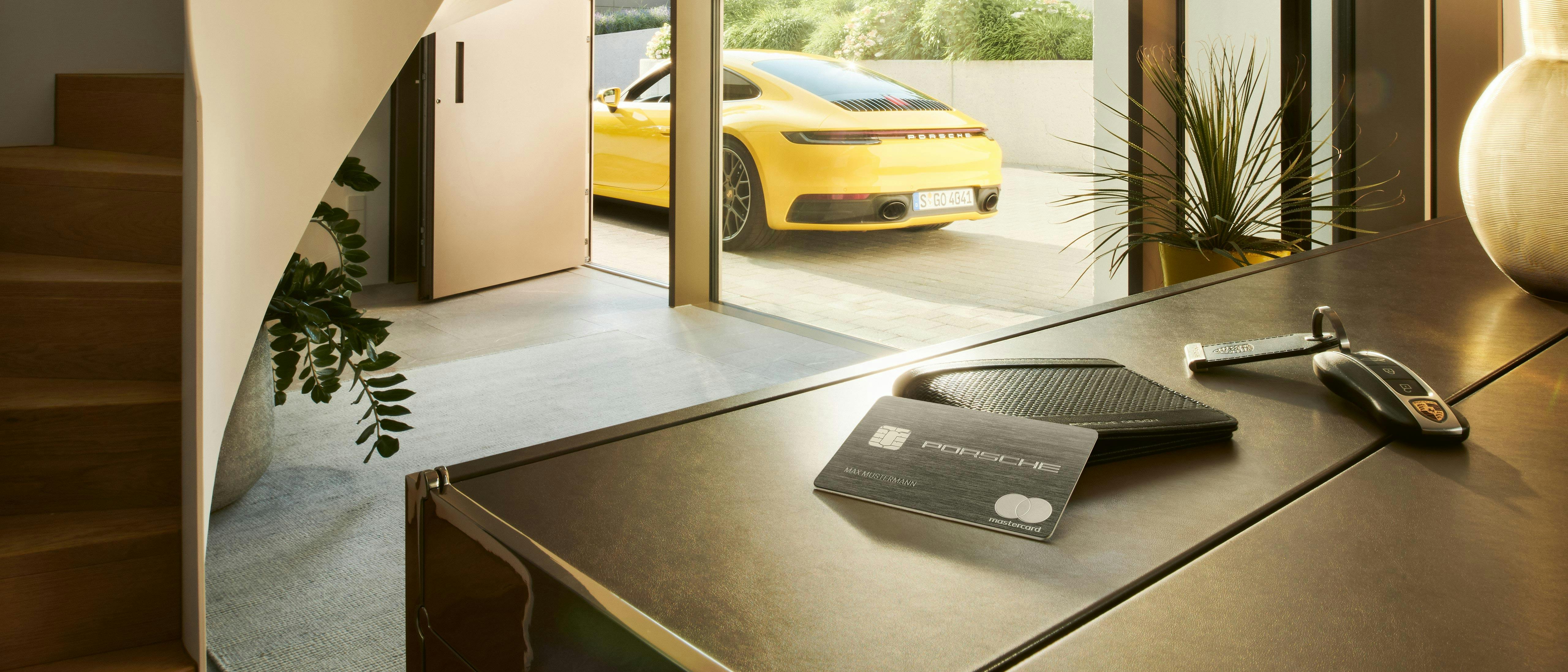 La carte Porsche est posée sur la table. Une voiture Porsche jaune est garée en arrière-plan.
