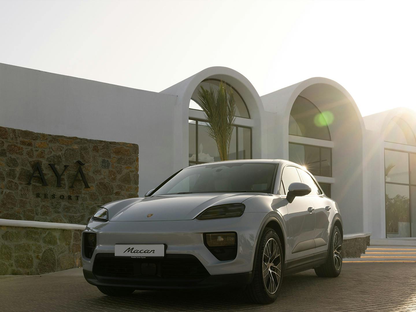 White Porsche Macan parked in front of the AYA Resort in Cyprus at sunset.
