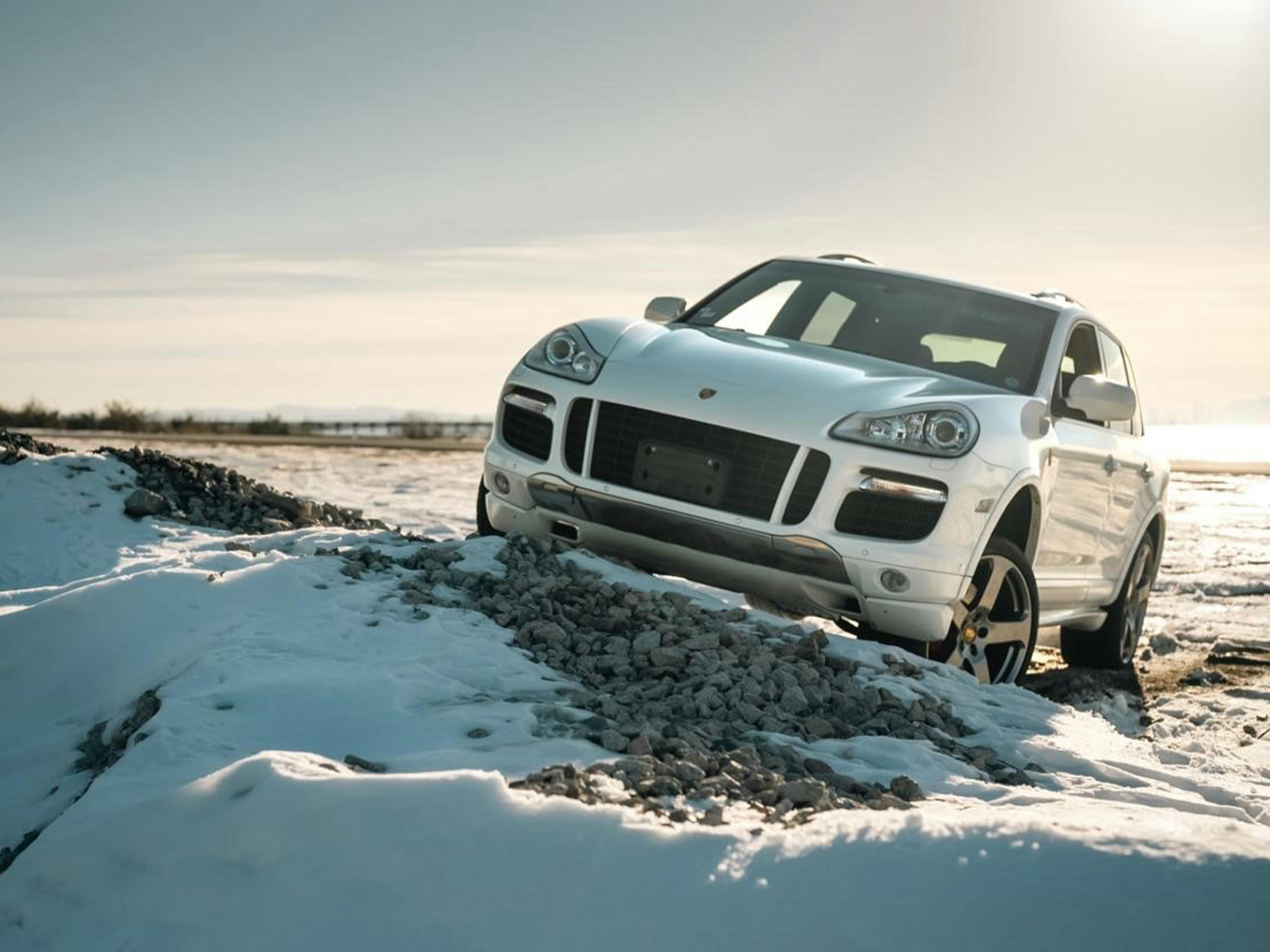 Vancouver – A white Porsche Cayenne pictured off-road, navigating snowy and rocky terrain.