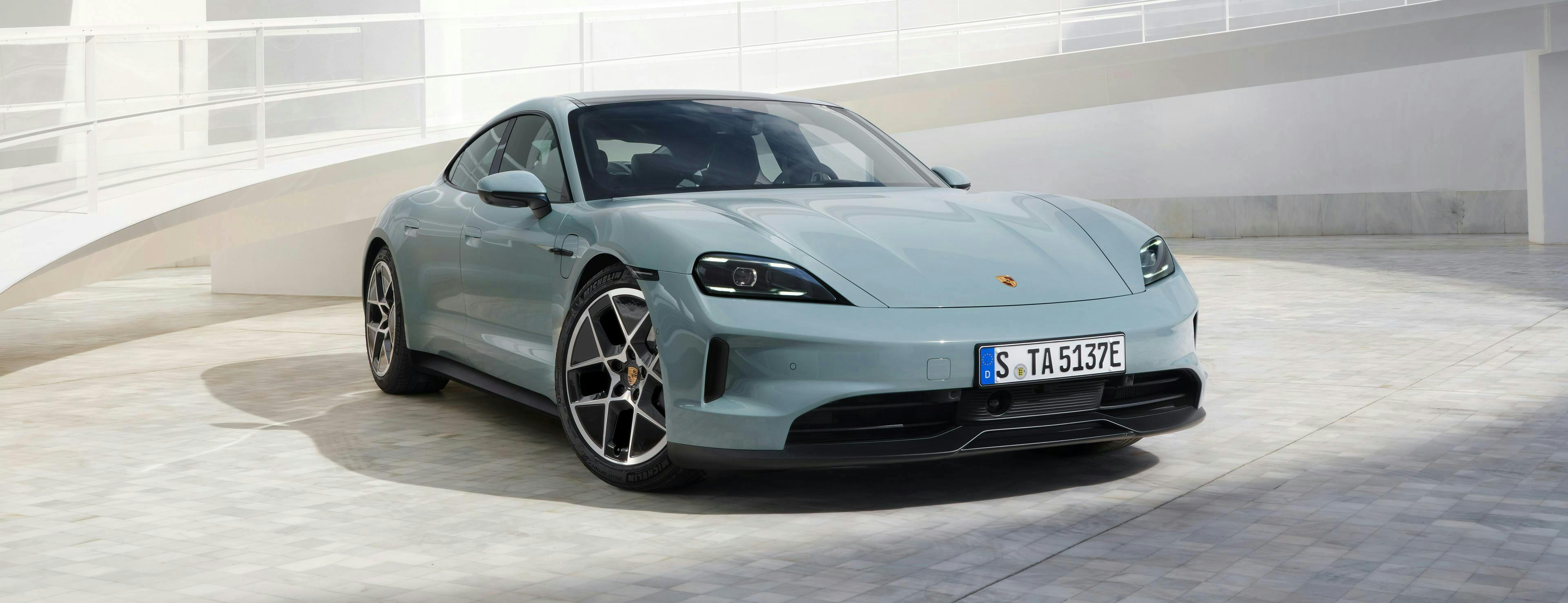Εντυπωσιακή μπροστινή όψη της νέας Porsche Taycan σε εξωτερικό χώρο.
