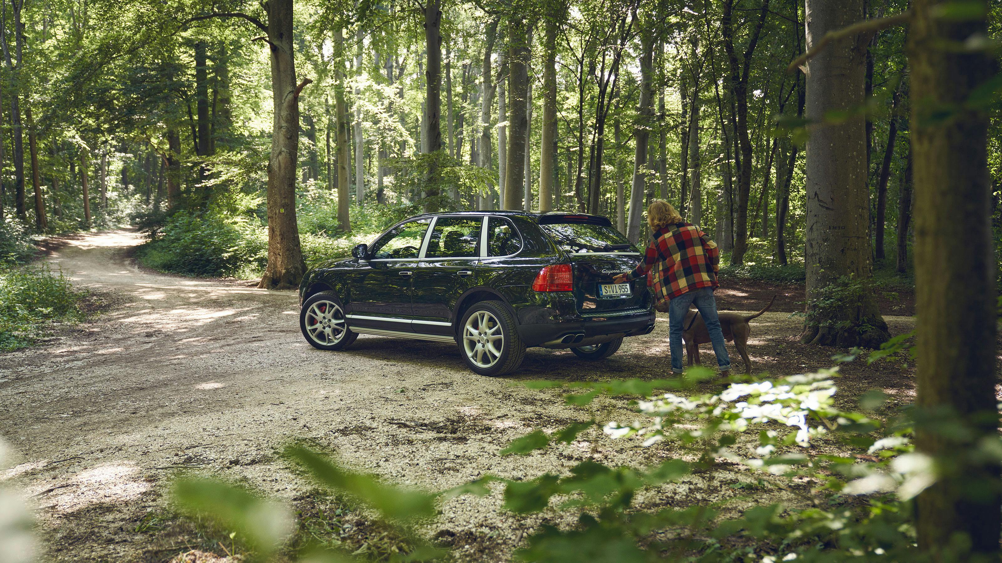 Porsche Cayenne E1 Hybrid, Dark Blue, forest scene – man with dog.