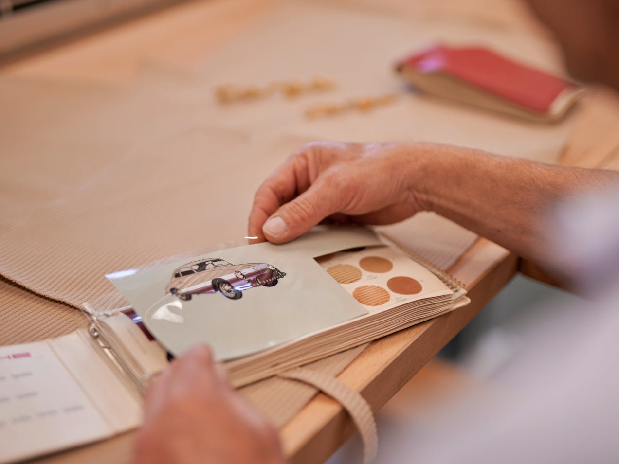 A fabric card with a sketch of a classic Porsche is picked up.