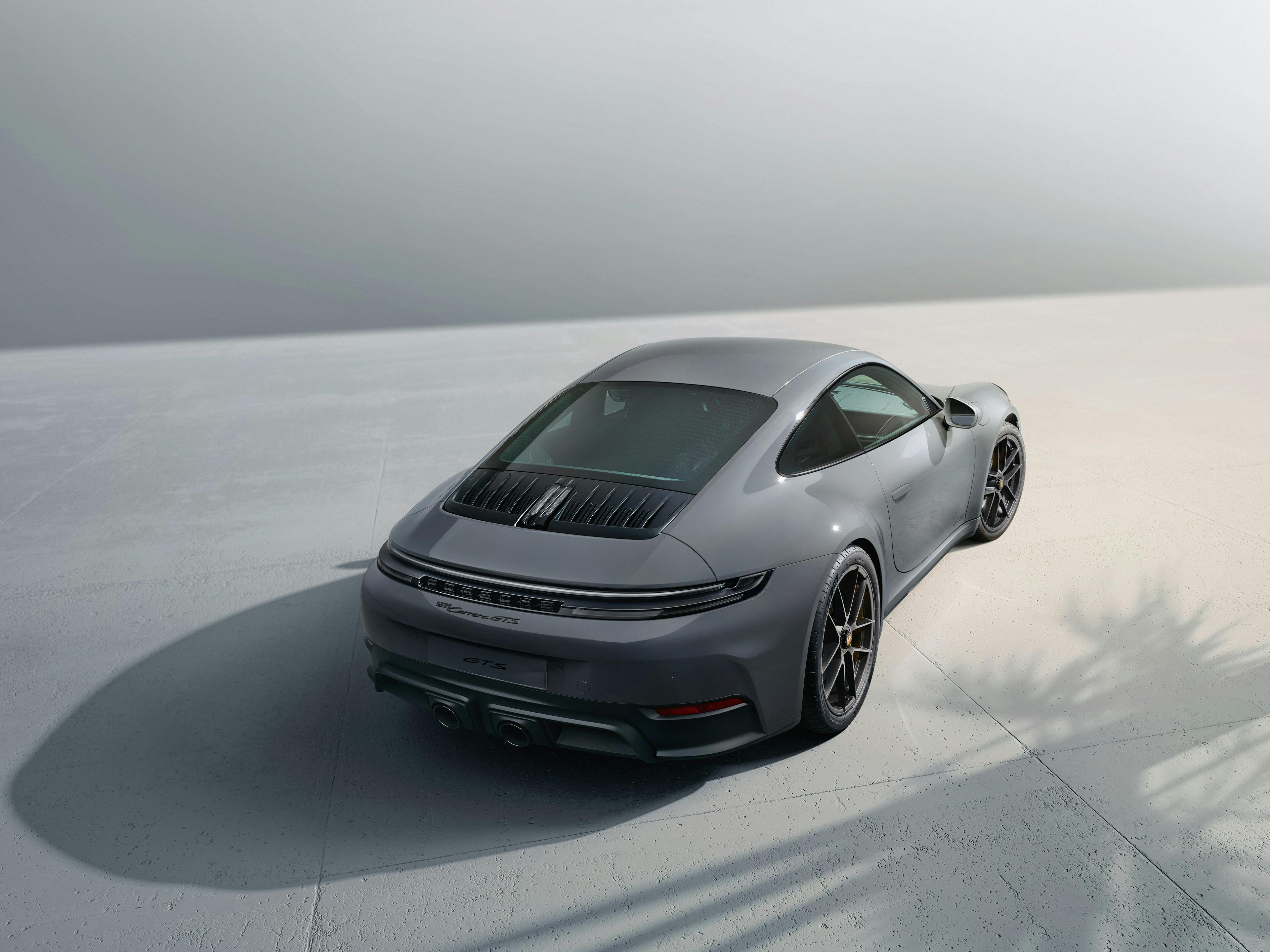 Vue de l'arrière d'une Porsche 911 Carrera GTS grise dans un studio blanc.