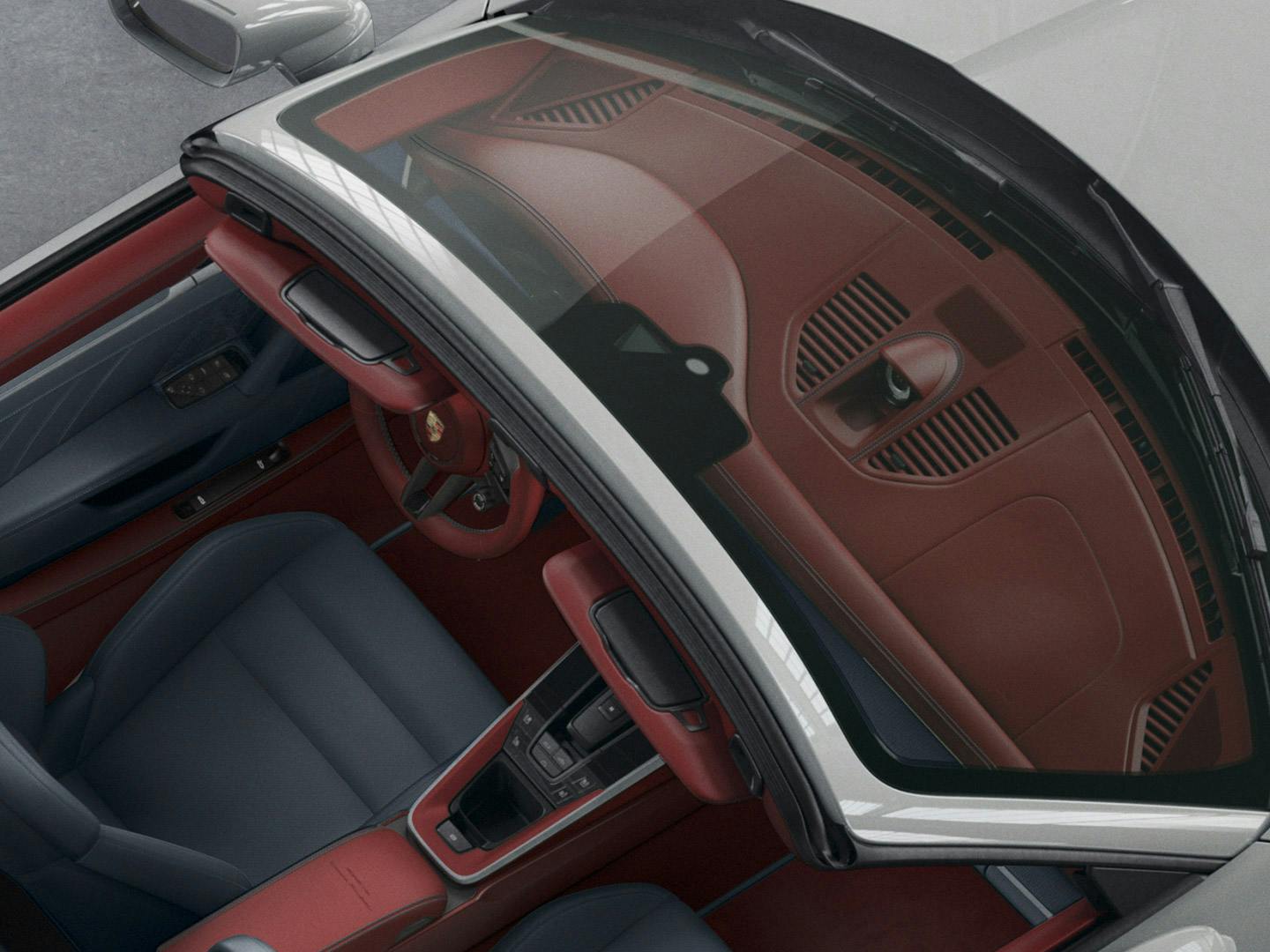 Interior view of a Porsche with a red dashboard, blue seats, and visible windshield details, showcasing luxury design and craftsmanship.