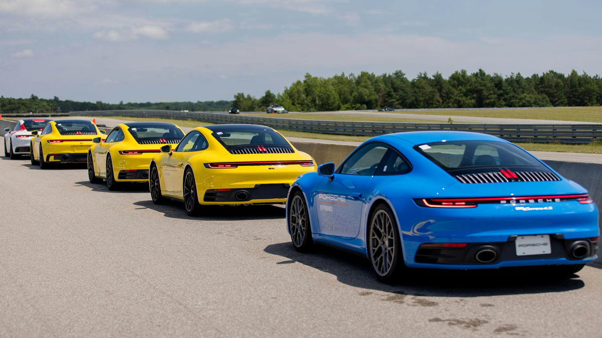 5 Porsche 911 garées en file indienne sur le bord d'une piste.