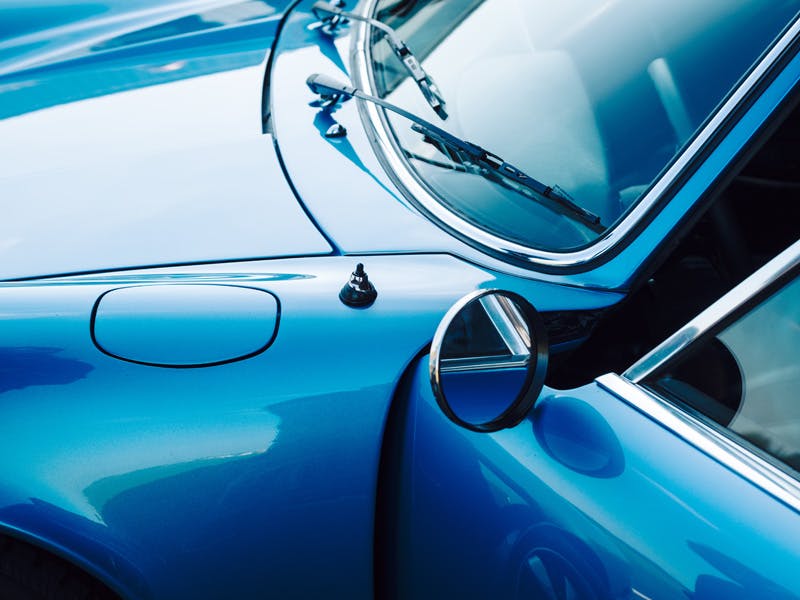 Detailaufnahme Porsche Classic: Außenspiegel, Tür, Frontscheibe mit Scheibenwischer.
