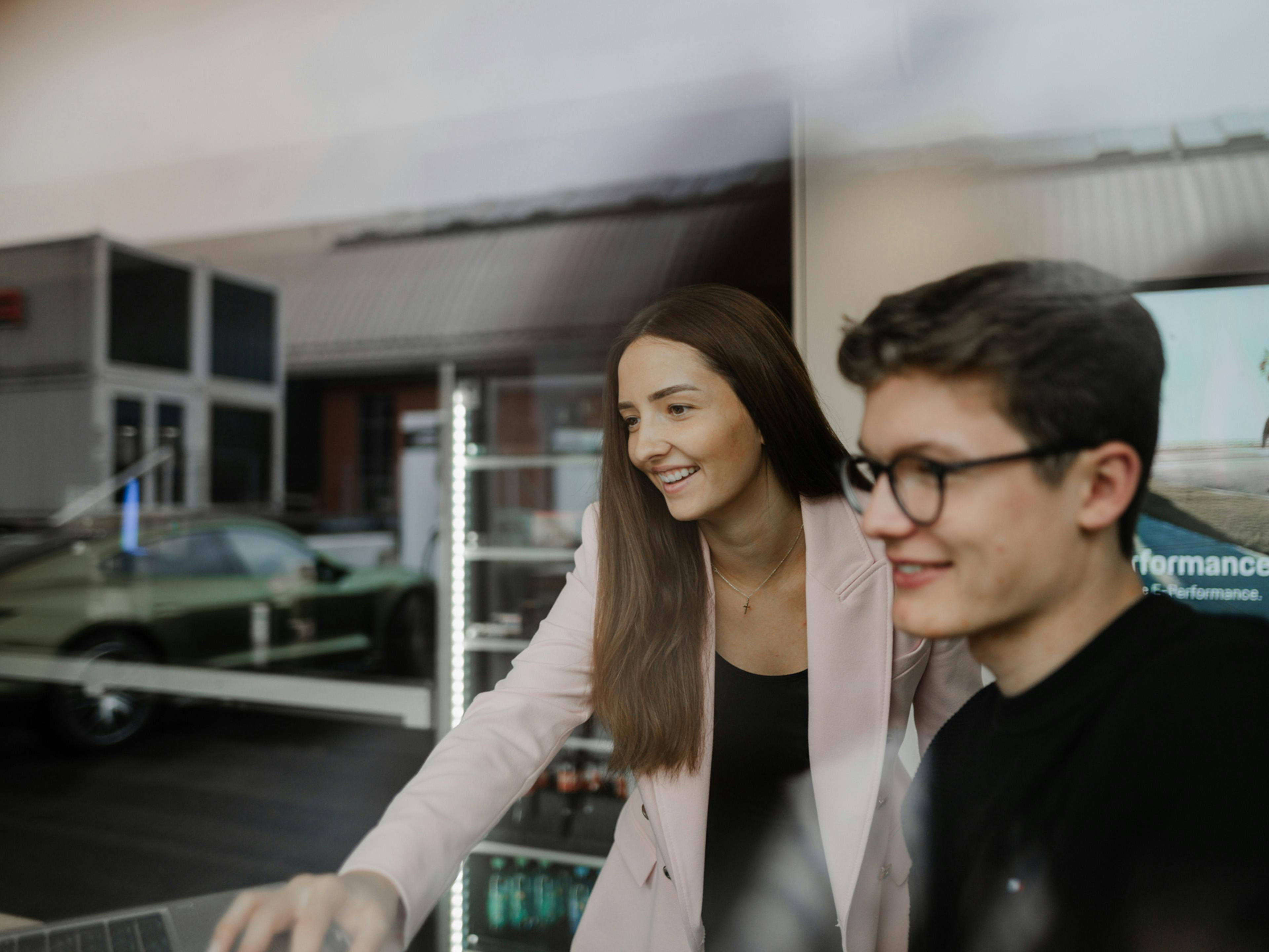 Zwei Studierende bei Porsche arbeiten gemeinsam an einem Arbeitsplatz.