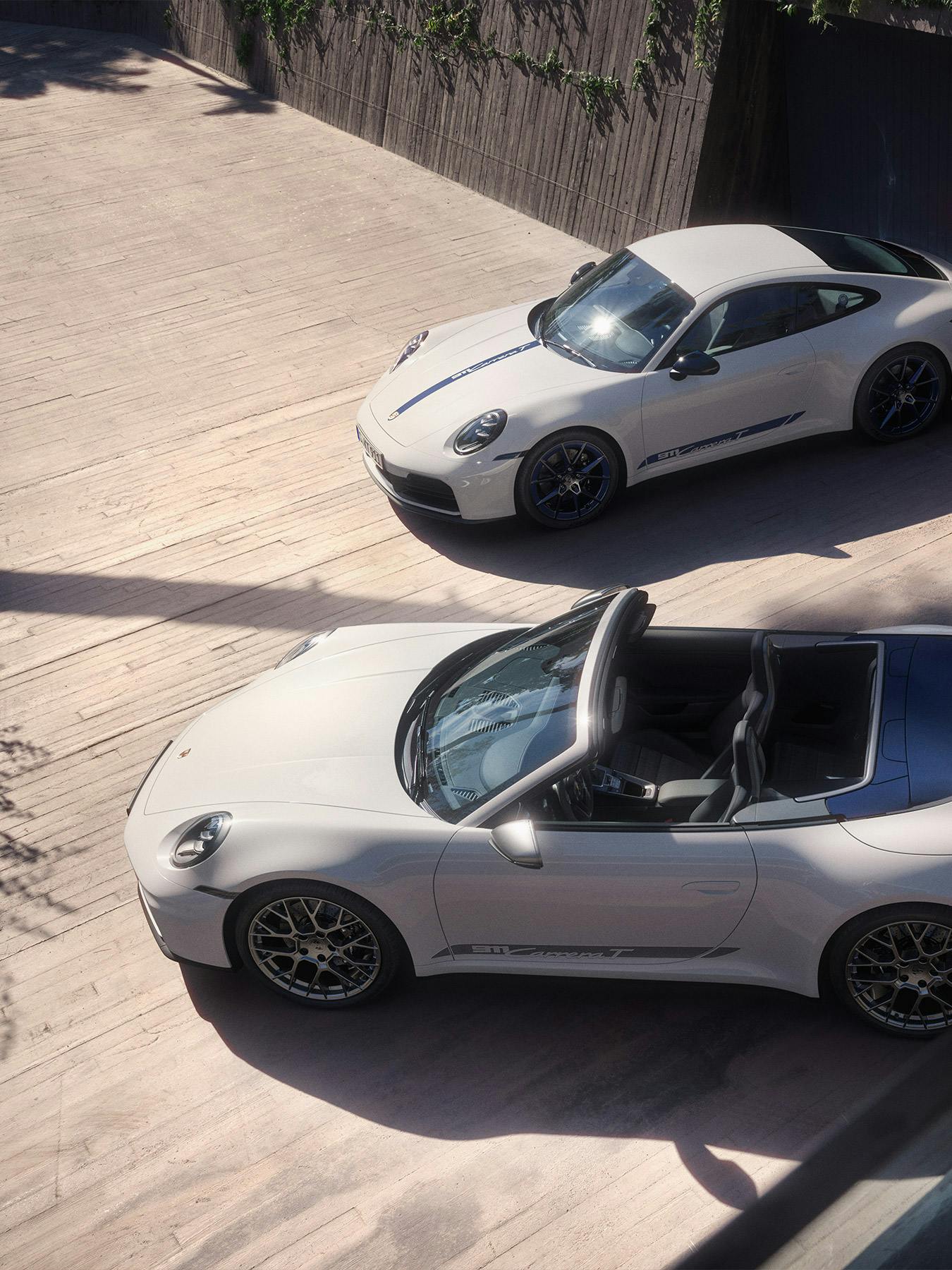 Two Porsche 911 parked in the shade of a tree.