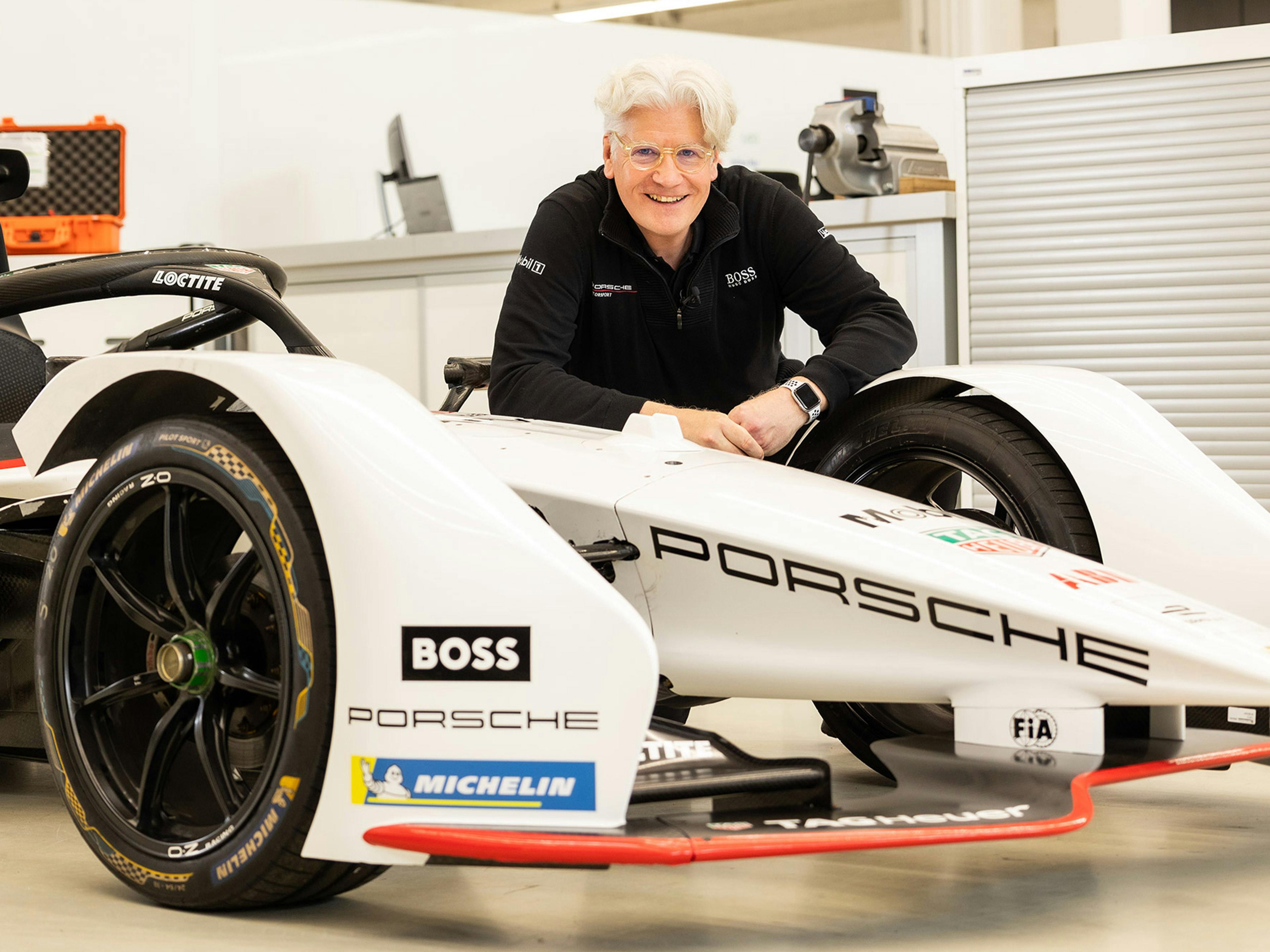 Der Porsche Mitarbeiter Martin posiert vor einem Testfahrzeug in einer Entwicklungswerkstatt.