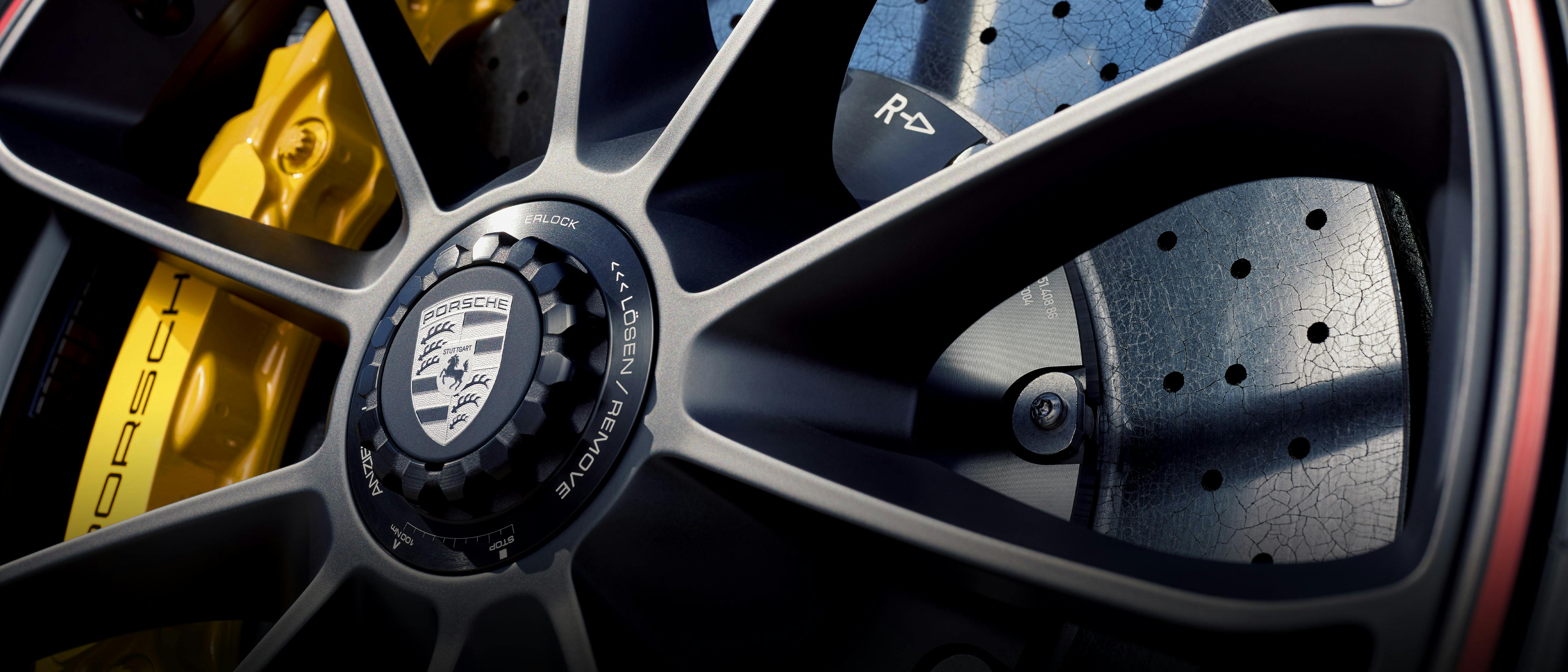 Close-up of a Porsche rim with yellow brake calliper and perforated brake disc.