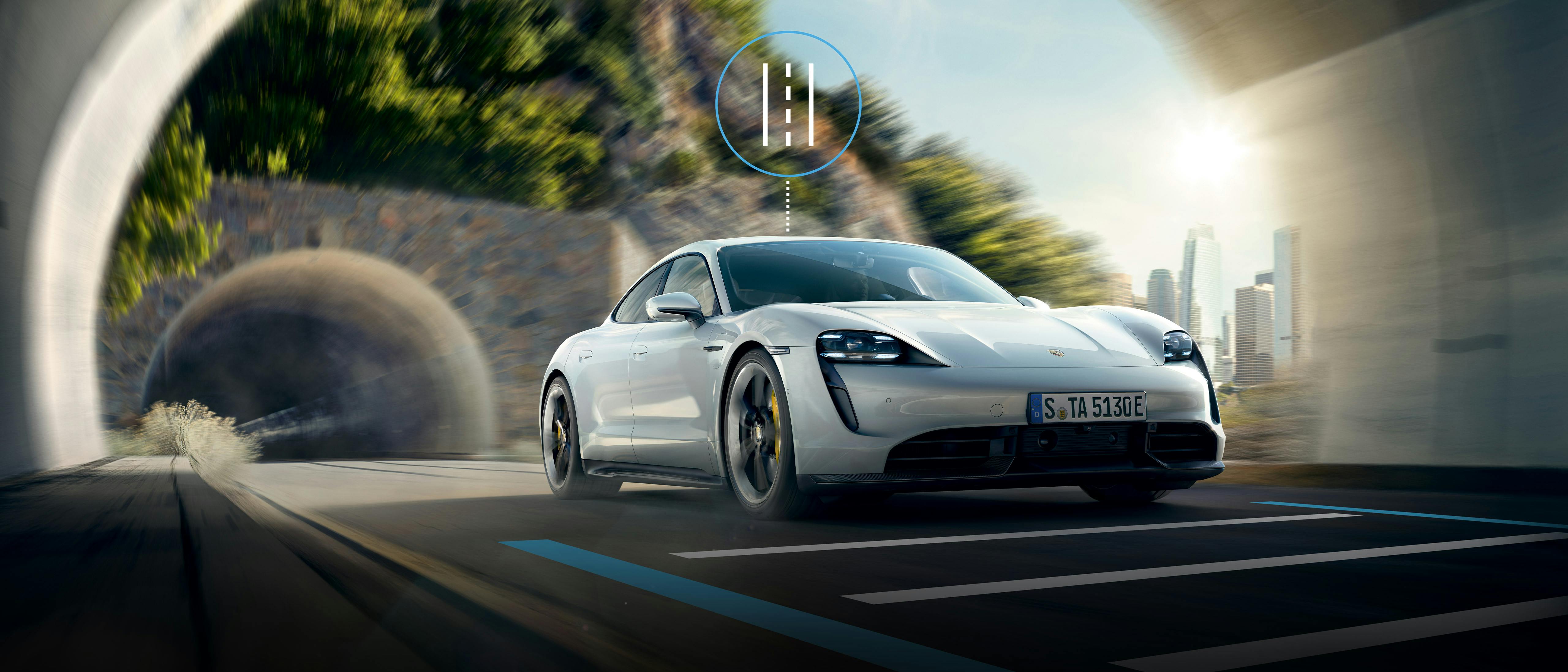Une Porsche Taycan Turbo s blanche entre dans un tunnel. Le guidage actif sur la voie est représenté graphiquement sur l'image.