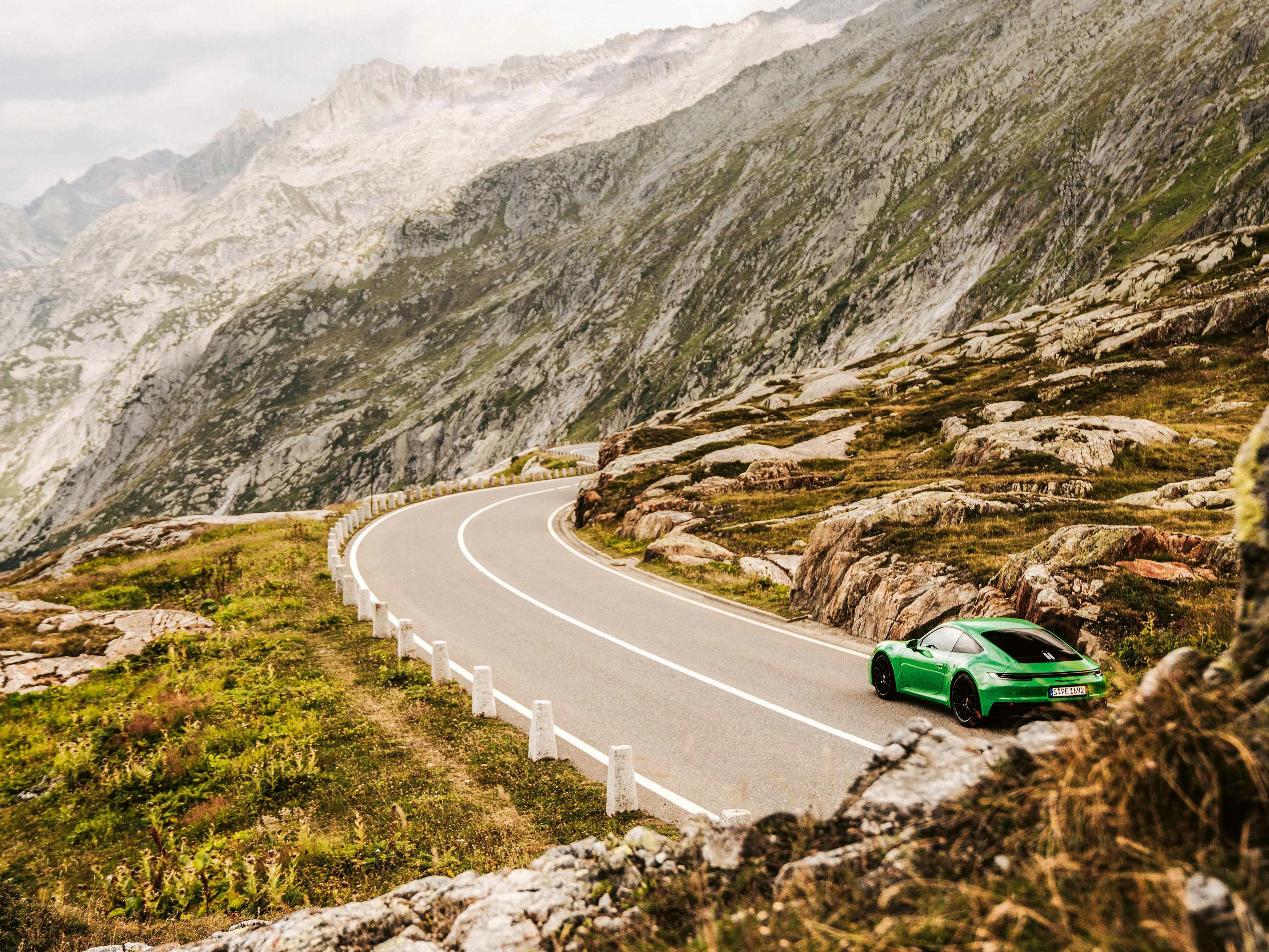 Un vehículo Porsche circulando por carreteras sinuosas en las montañas.