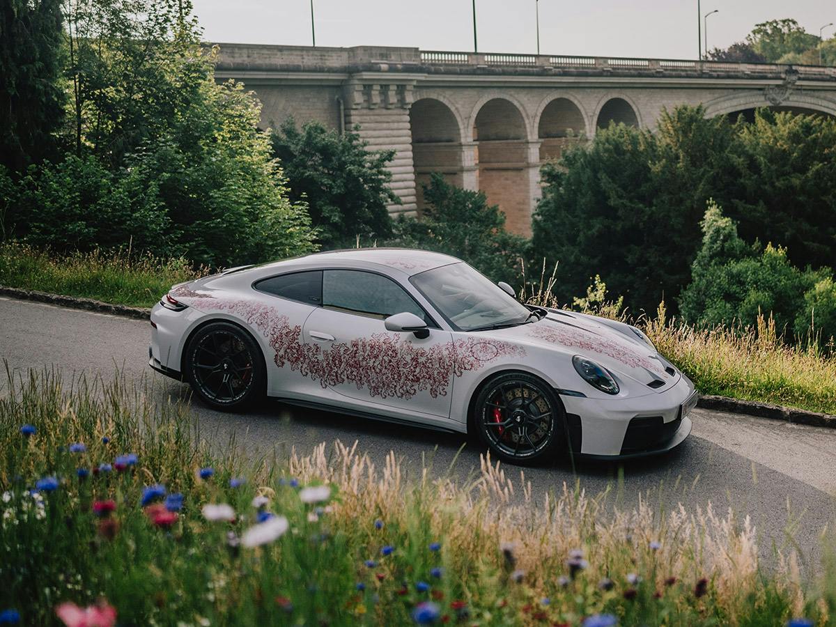 A 911 GT3 Touring in individual colour Racing Green Metallic on a road in the mountains.