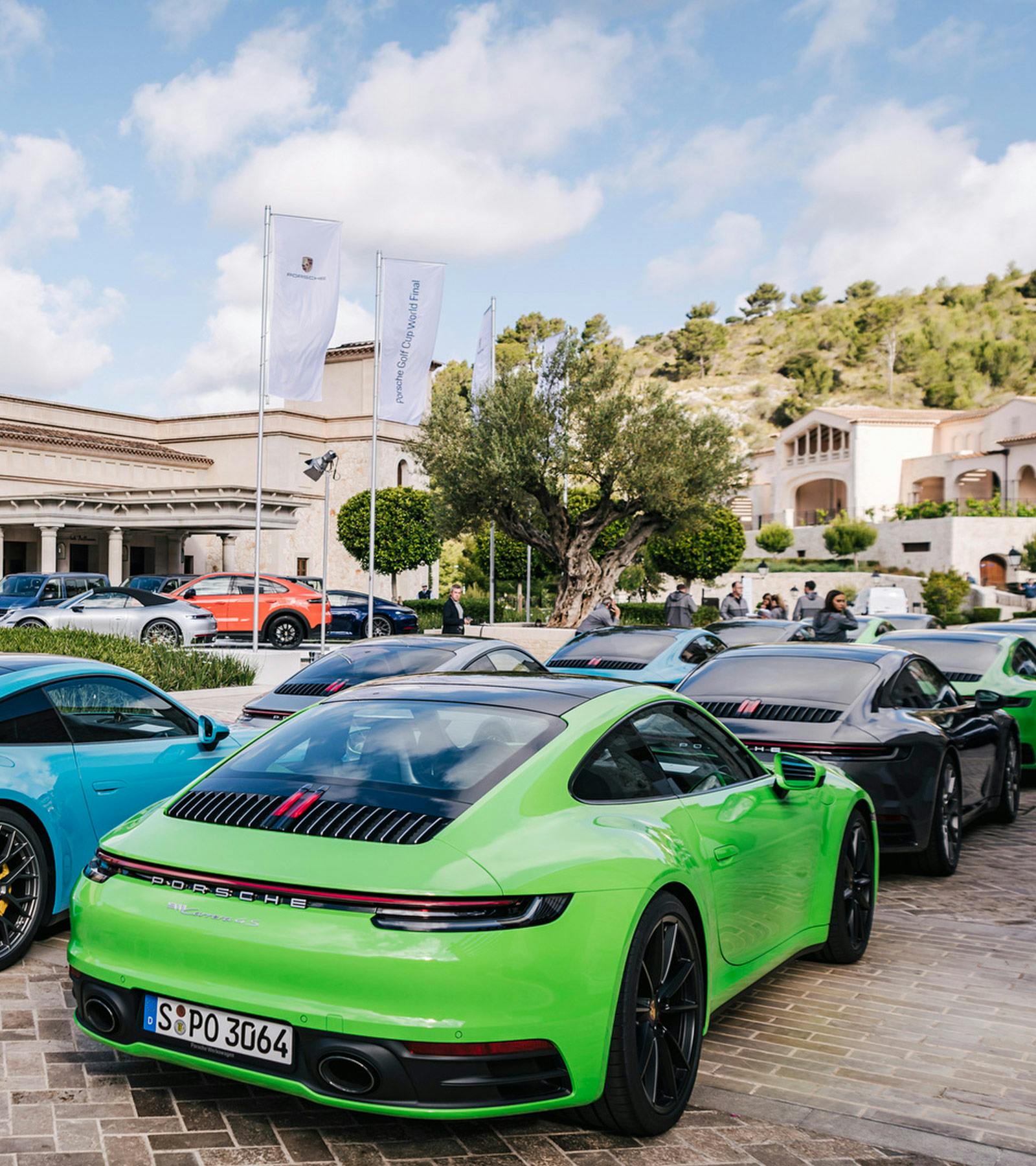 Etliche vor einem Gebäude geparkte Porsche Fahrzeuge