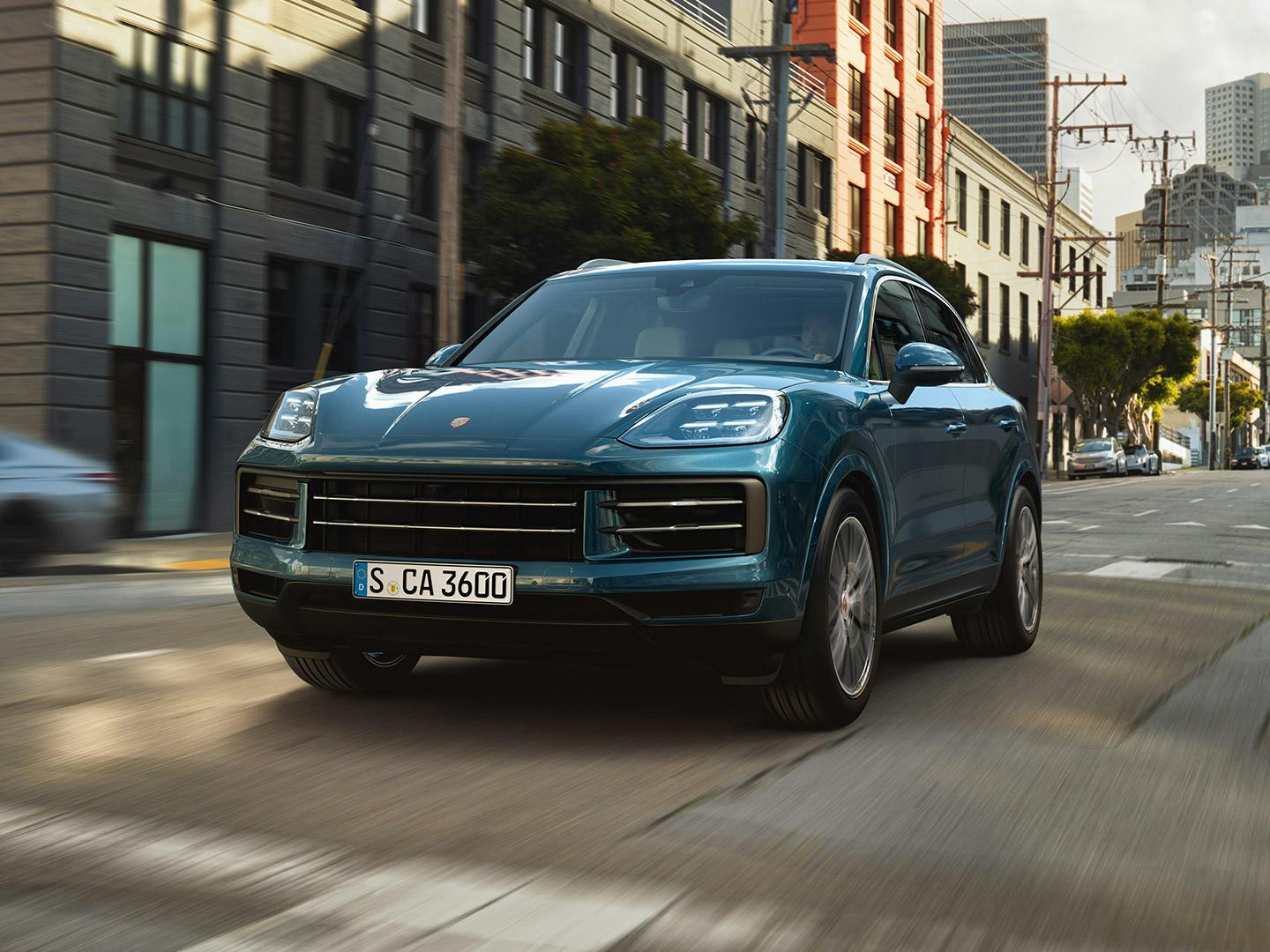 Une Porsche Cayenne bleue roule dans une rue de la ville.