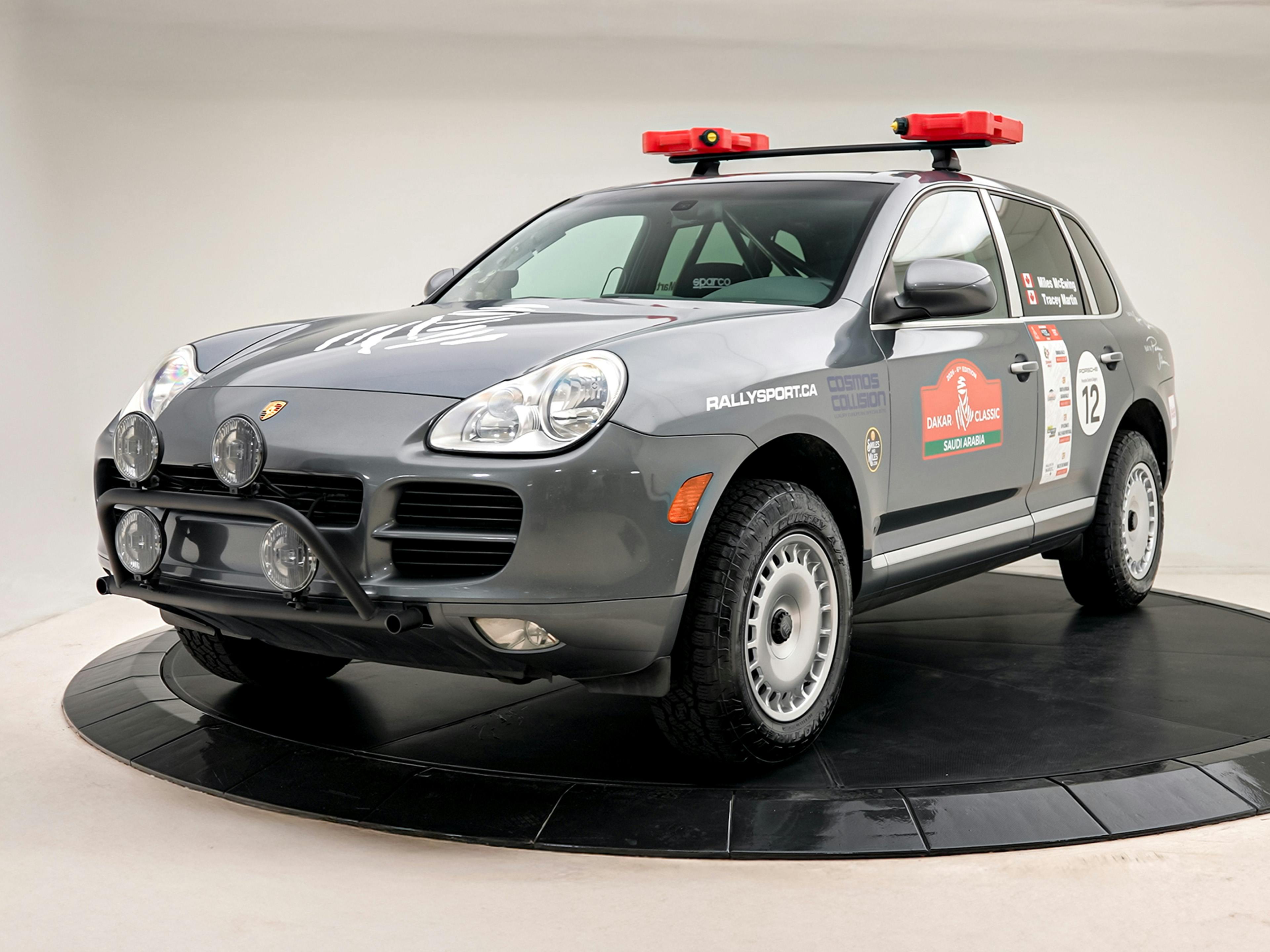 Calgary – A grey Porsche Cayenne powers through a snowy landscape, kicking up a cloud of snow behind it.