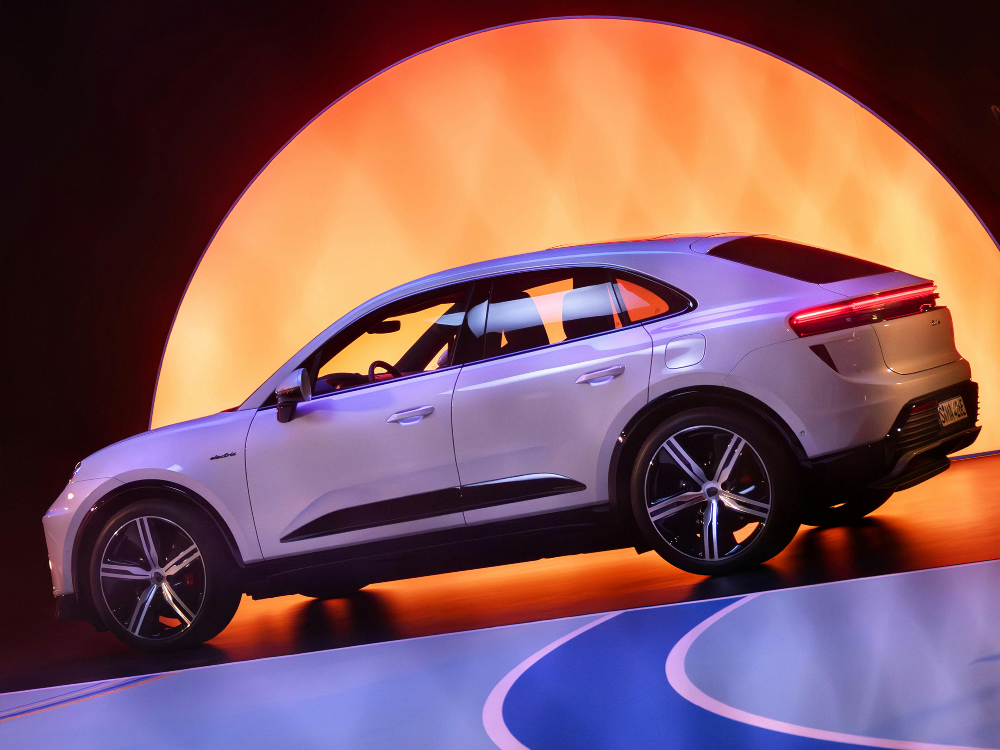 Side profile of Porsche Macan in vibrant studio lighting and sunset backdrop.