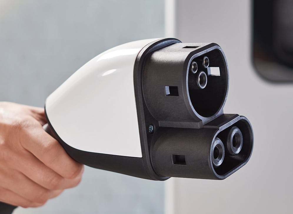 A hand holding a CCS2 charging plug.