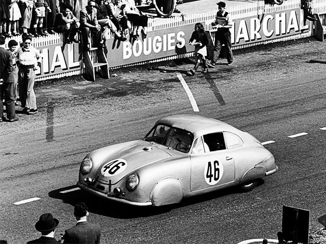 Porsche 356 SL with race number 46 on track; spectators behind barrier with advertising signs, black and white, early 1950s