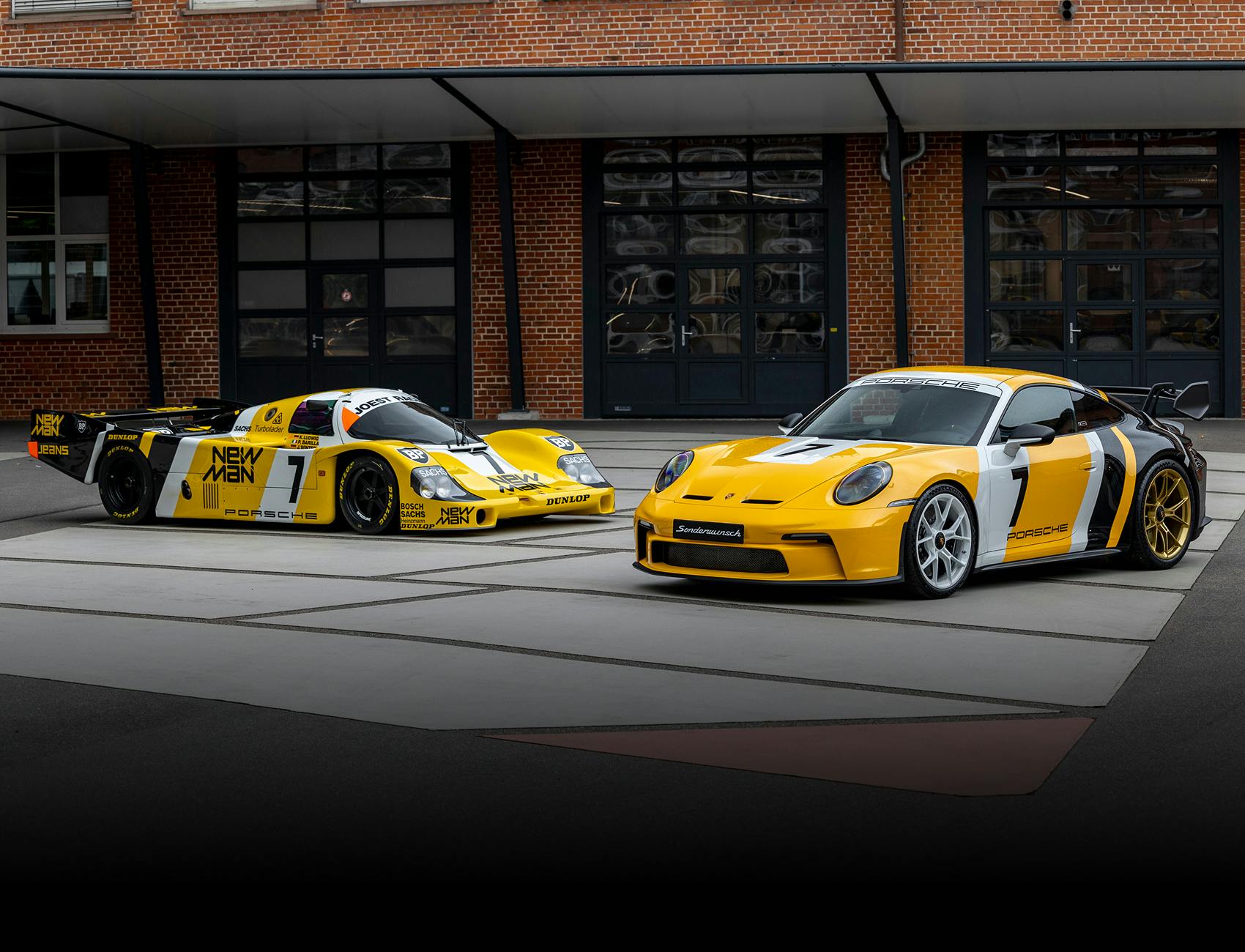 911 GT3 (992) – Le Mans 1985 en de winnende auto van Le Mans in 1985 staan naast elkaar voor garages.