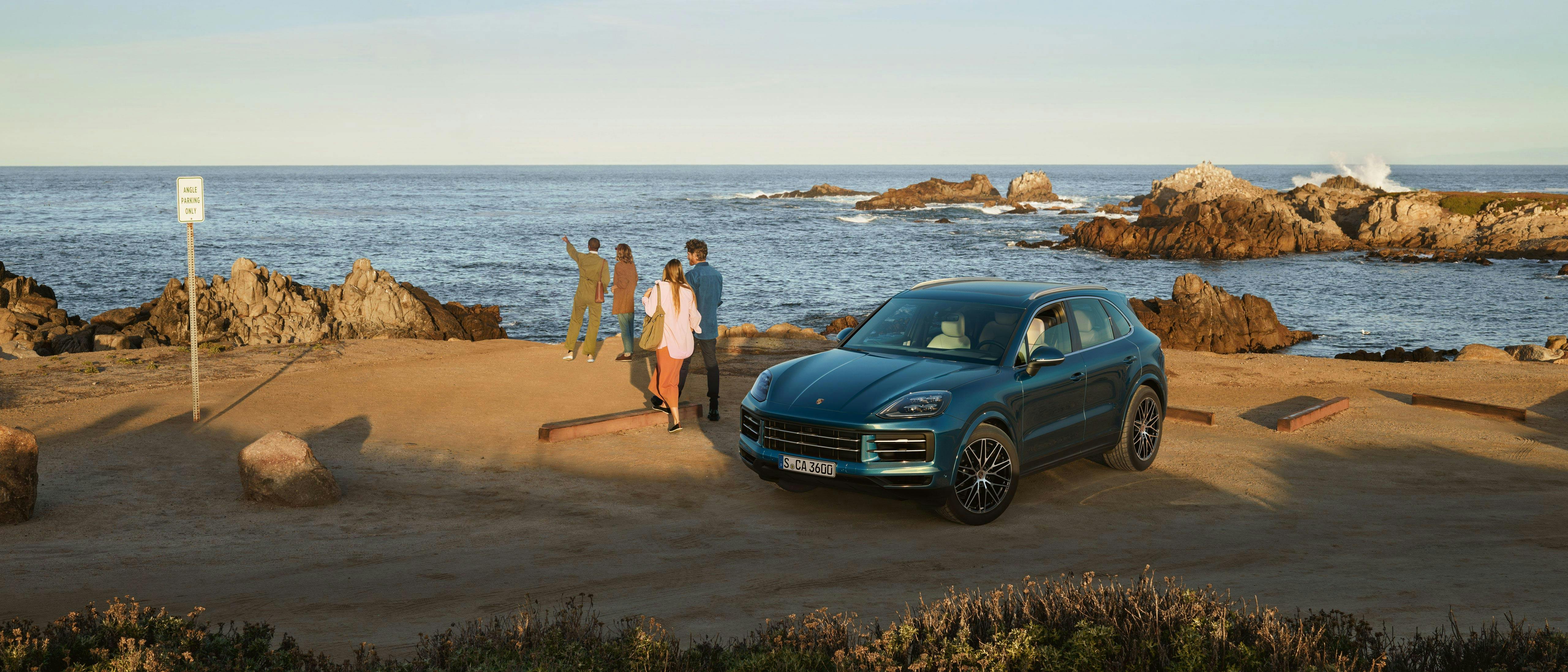 Family standing by blue Cayenne parked next to the ocean