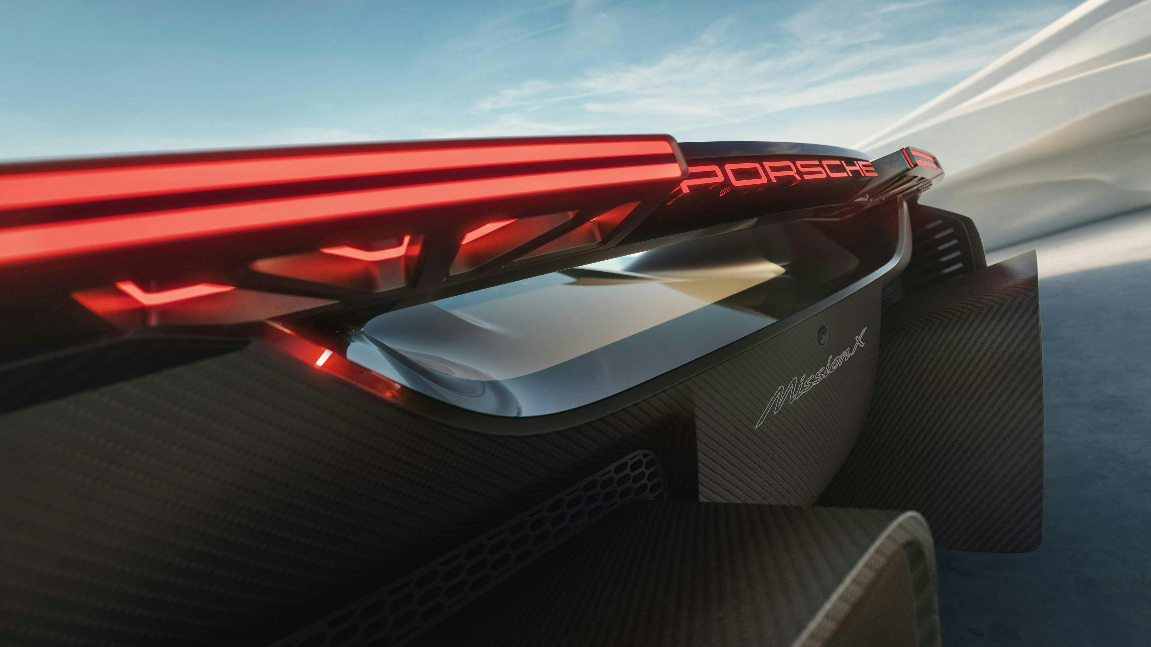 波のような建築物の前に停まっているロケットメタリックのPorsche Mission X 近未来的なテールライトを備えたリアの詳細ビュー