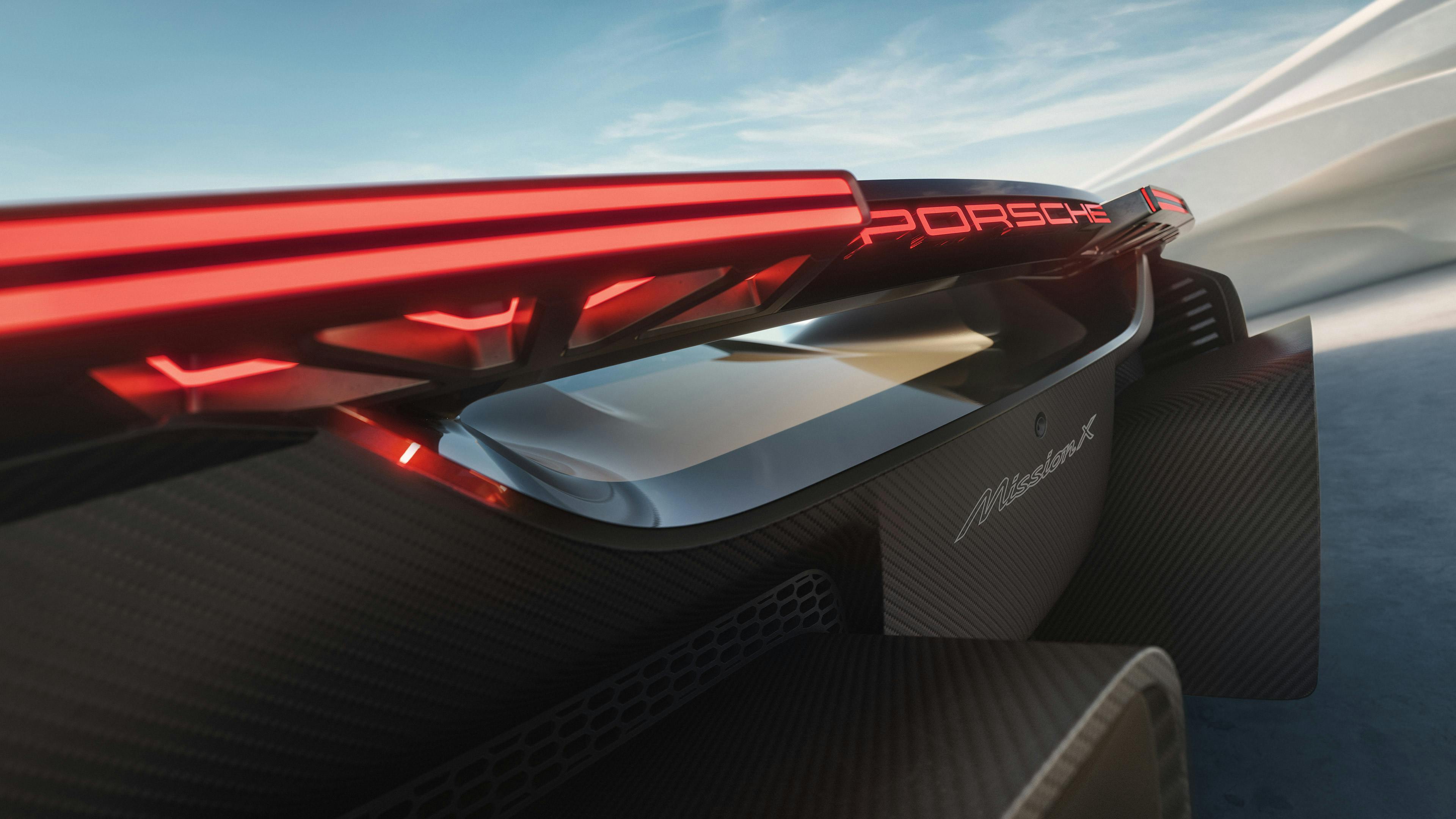 La Porsche Mission X de couleur Rocket Metallic devant une architecture onduleuse. Vue détaillée de l’arrière aux feux futuristes.