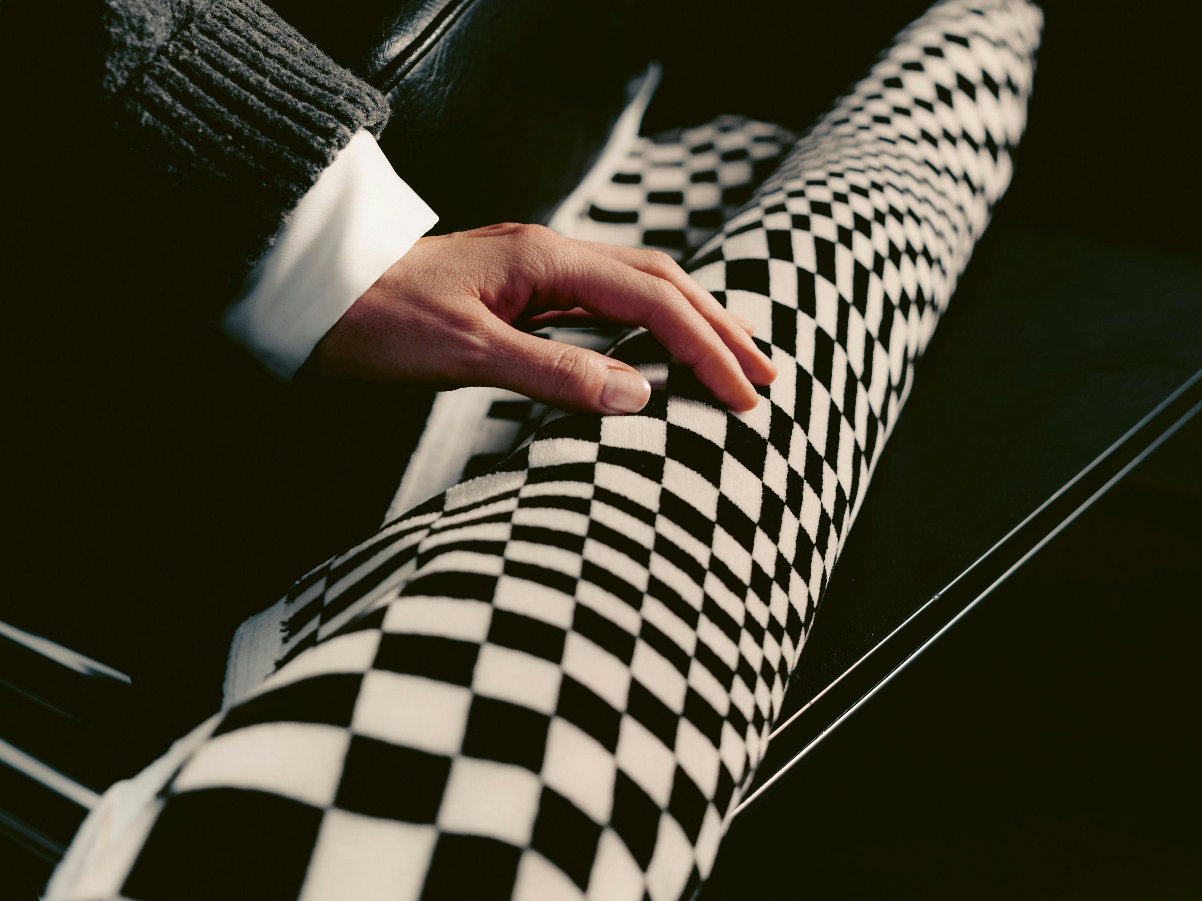 A hand in a dark grey knitted sleeve touches a Porsche Pascha fabric.