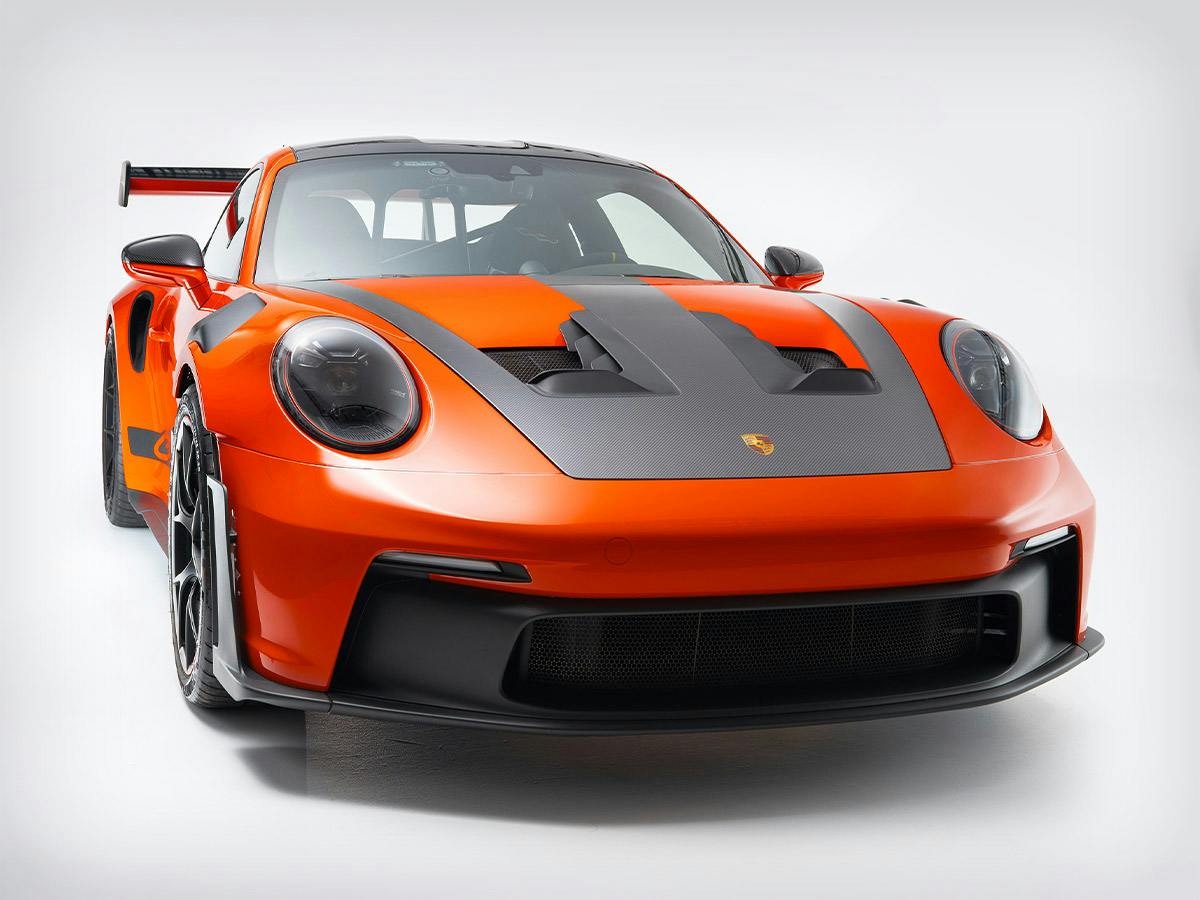 Front view of the 911 GT3 RS in Paint to Sample Lavaorange with carbon aero elements, photographed in a white studio.