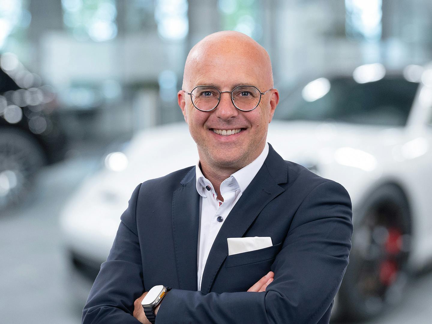 Porsche Mitarbeiterin berät einen Kunden der in einem Porsche Fahrzeug sitzt.