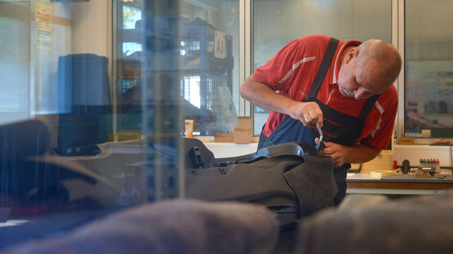 A Porsche employee works on a seat cushion