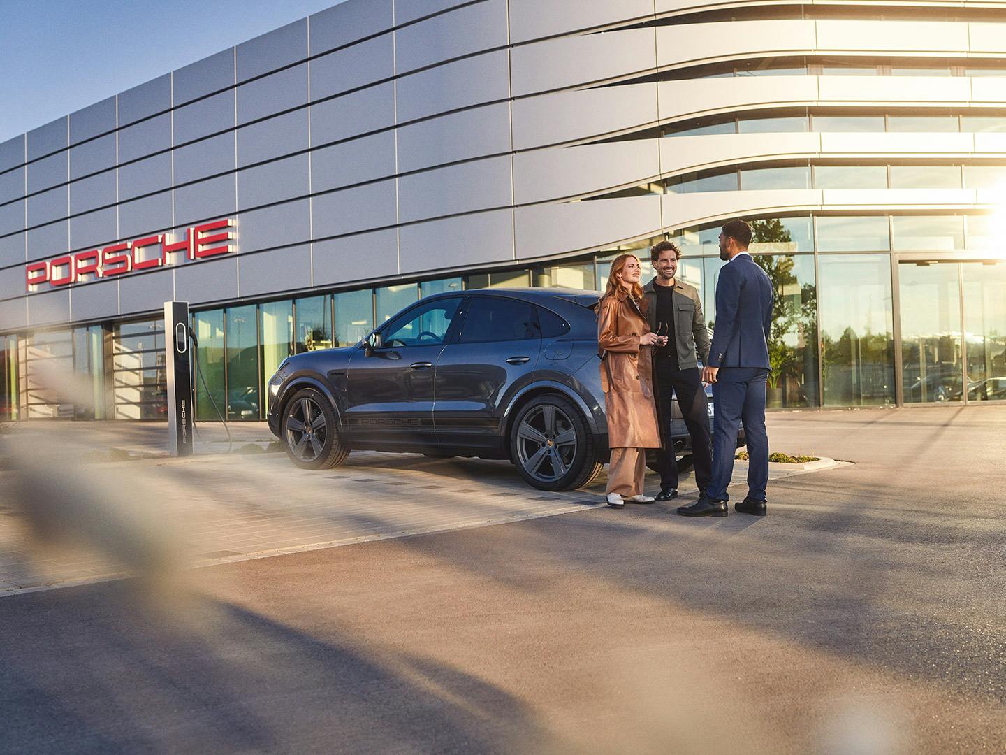 A couple meets with a Porsche representative outside of a Porsche Center.