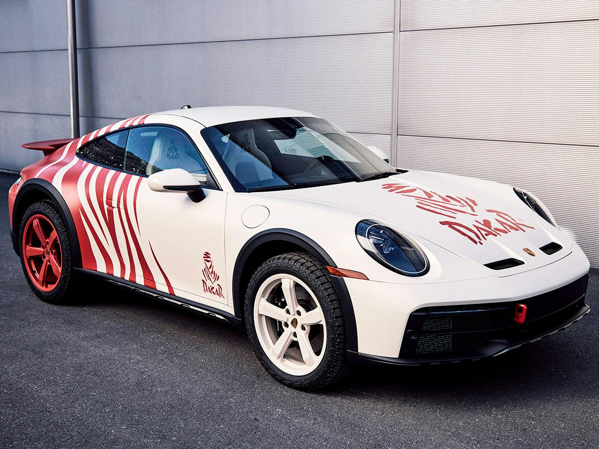 A 911 Dakar coloured in individual Design Painting in Tappan Red and white from the side with white front wheels and red back wheels.
